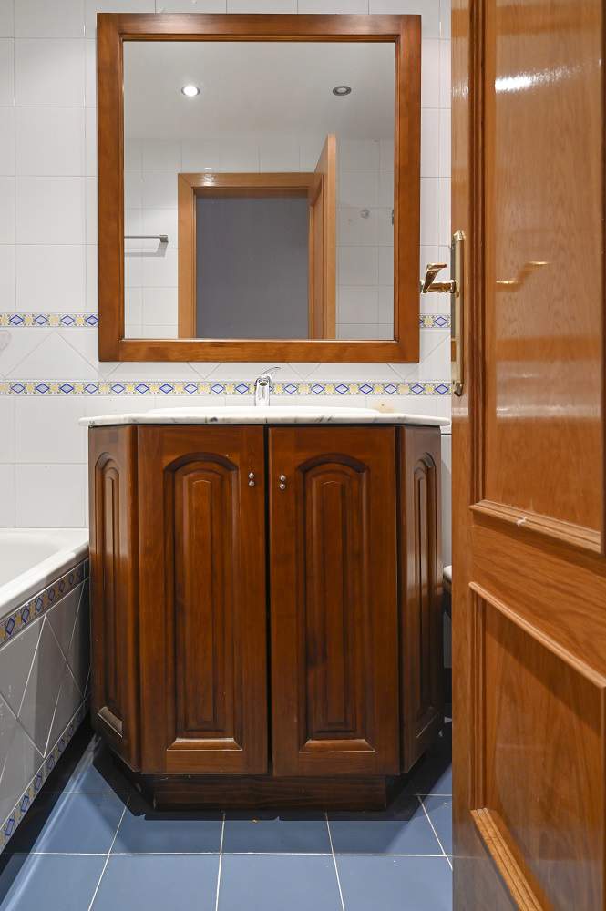 Lavabo y espejo de madera al lado de una bañera