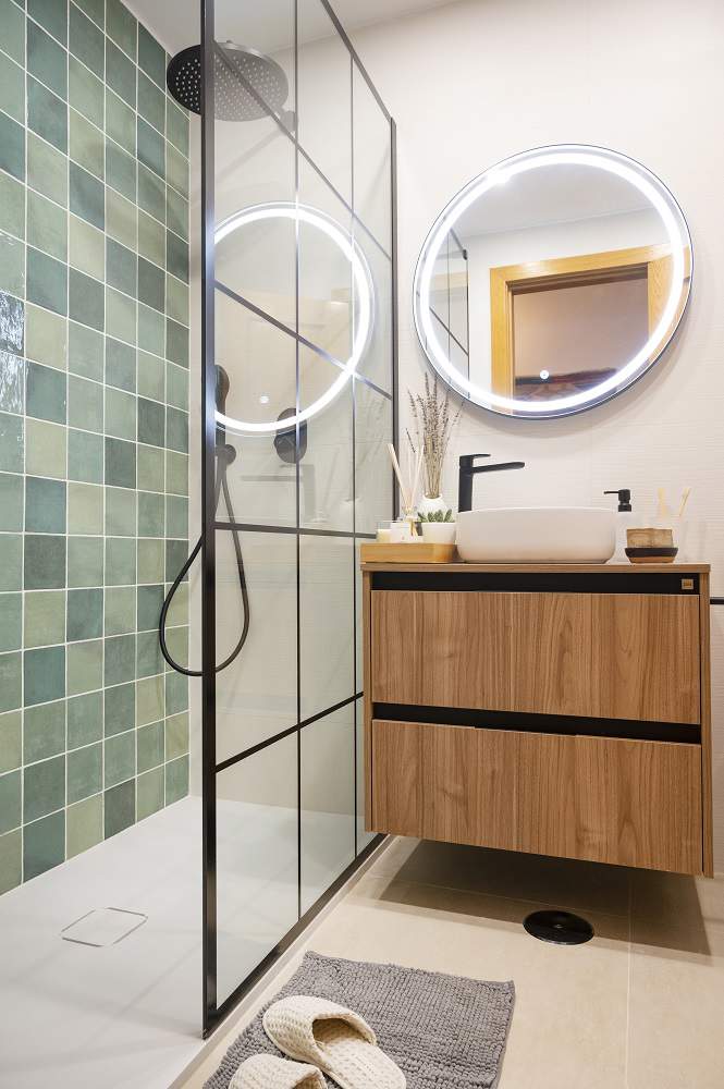 Un baño con ducha y mampara cuarteada y mueble de lavabo de madera.