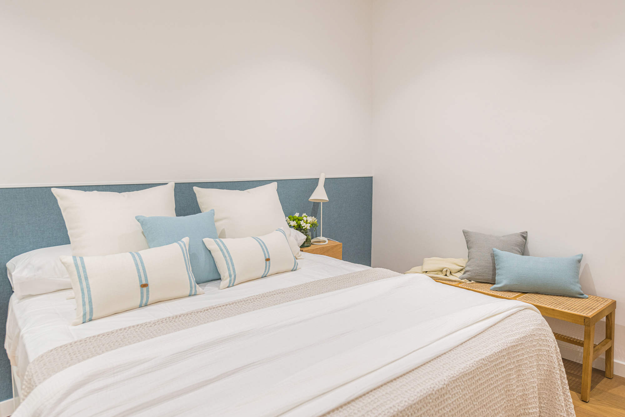 Dormitorio con cabecero azul y banco de fibras.