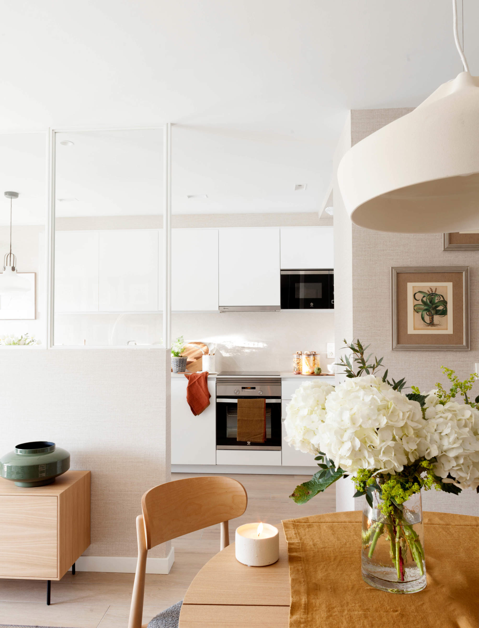 Un marco acristalado actúa como separación entre la cocina y el salón, ampliando visualmente toda la estancia.