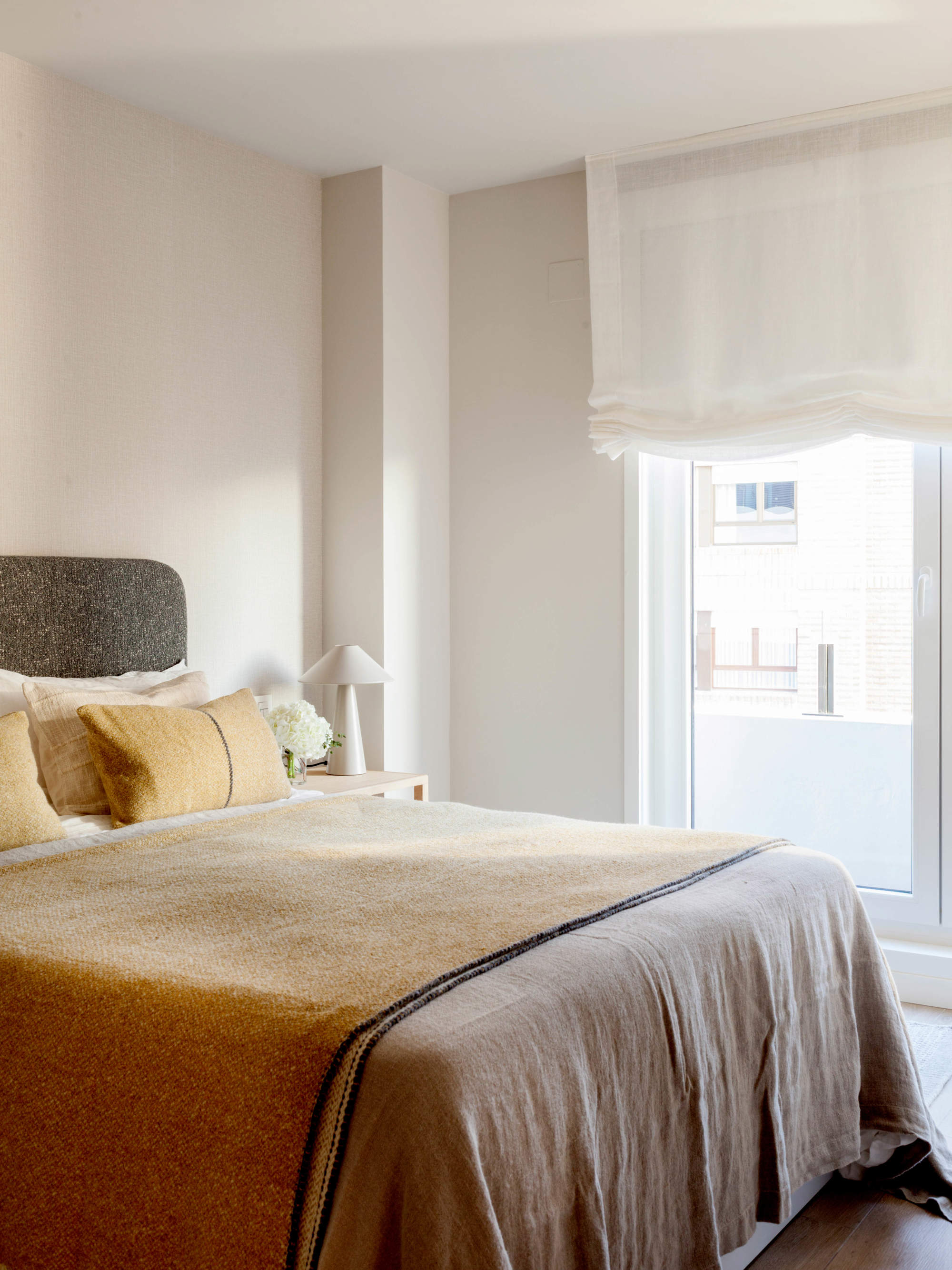 Habitación invitados con paredes en color crema y ropa de cama en tonos ocre.