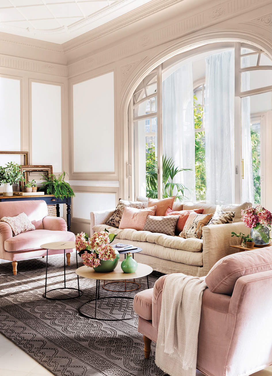 Salón decorado en tonos crudos y rosas, con mesas de centro redondas tipo nido y maxi alfombra con motivos geométricos.