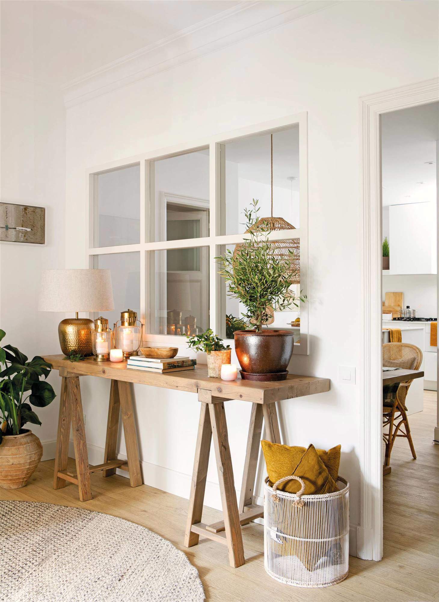Recibidor minimalista con mesa auxiliar de madera, elementos decorativos en dorado y plantas.