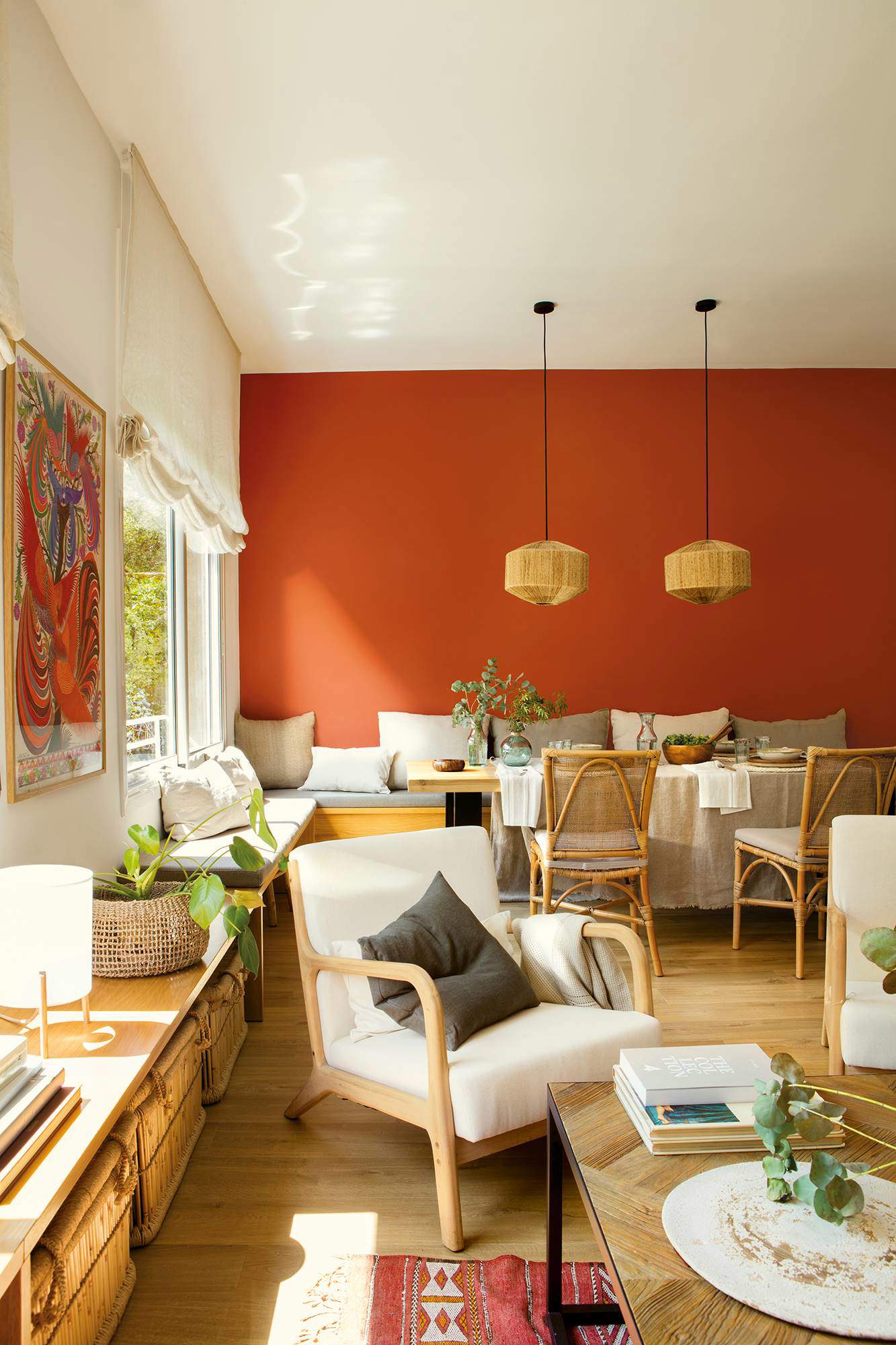 Salón abierto al comedor de estilo rústico con pared pintada de color terracota.