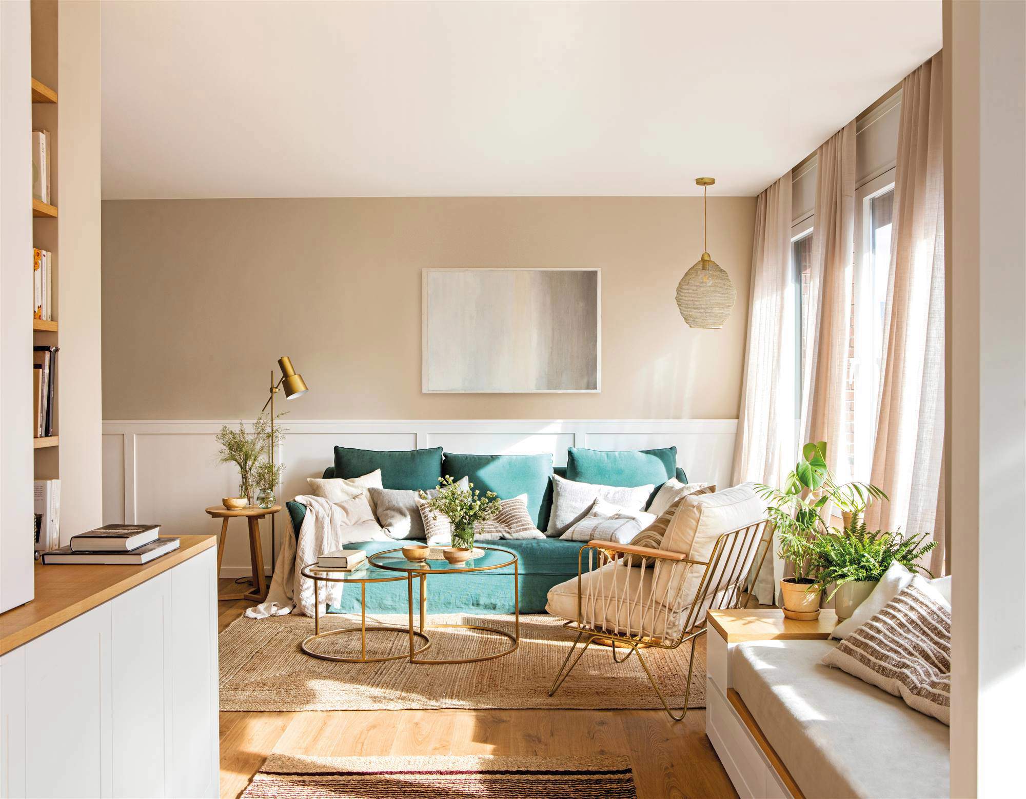 Salón con sofá azul, cortinas vaporosas y paredes beige con arrimadero. 