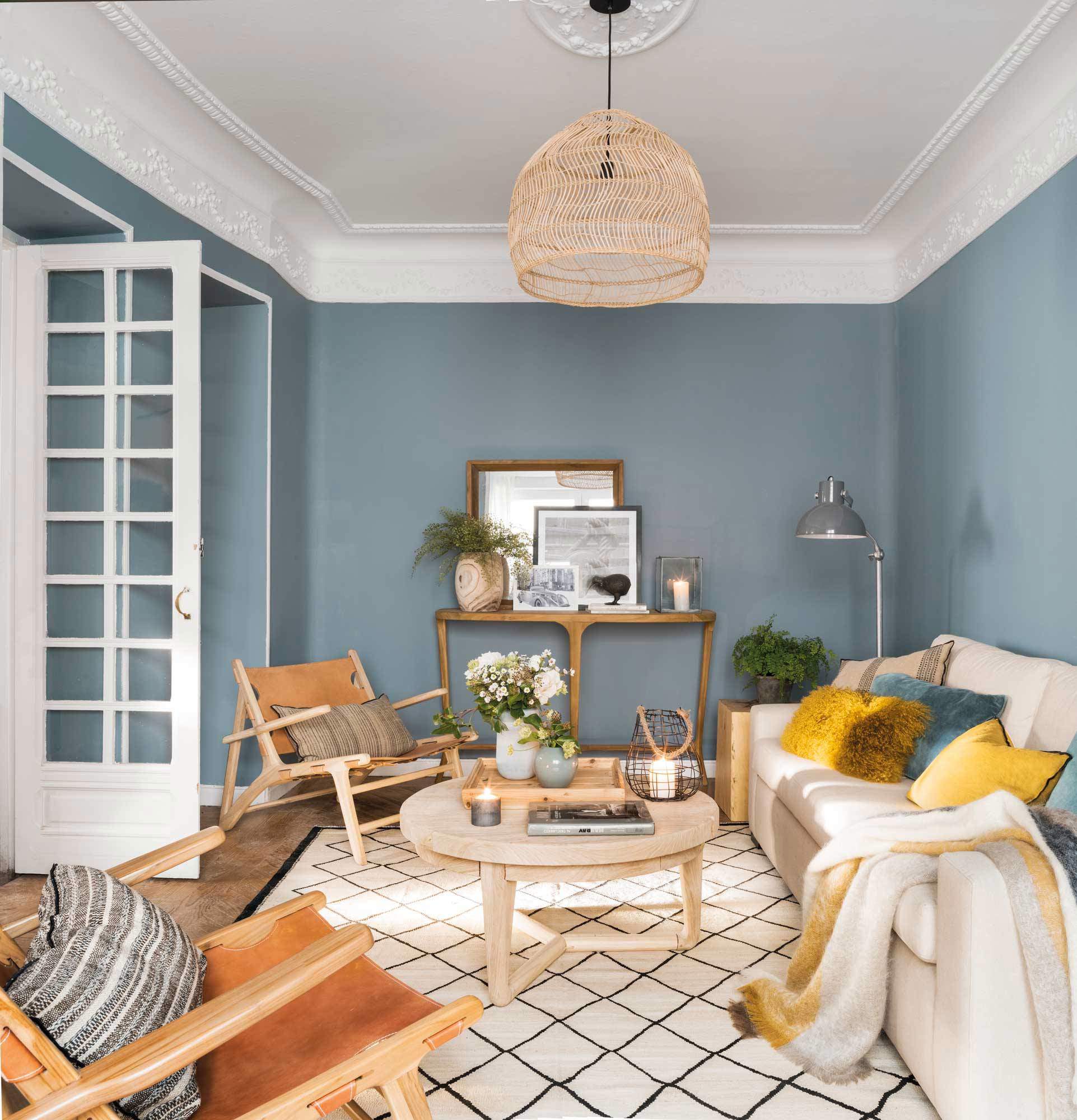 Salón con sofá, butacas, alfombra de cuadros, molduras y paredes azules marinas.