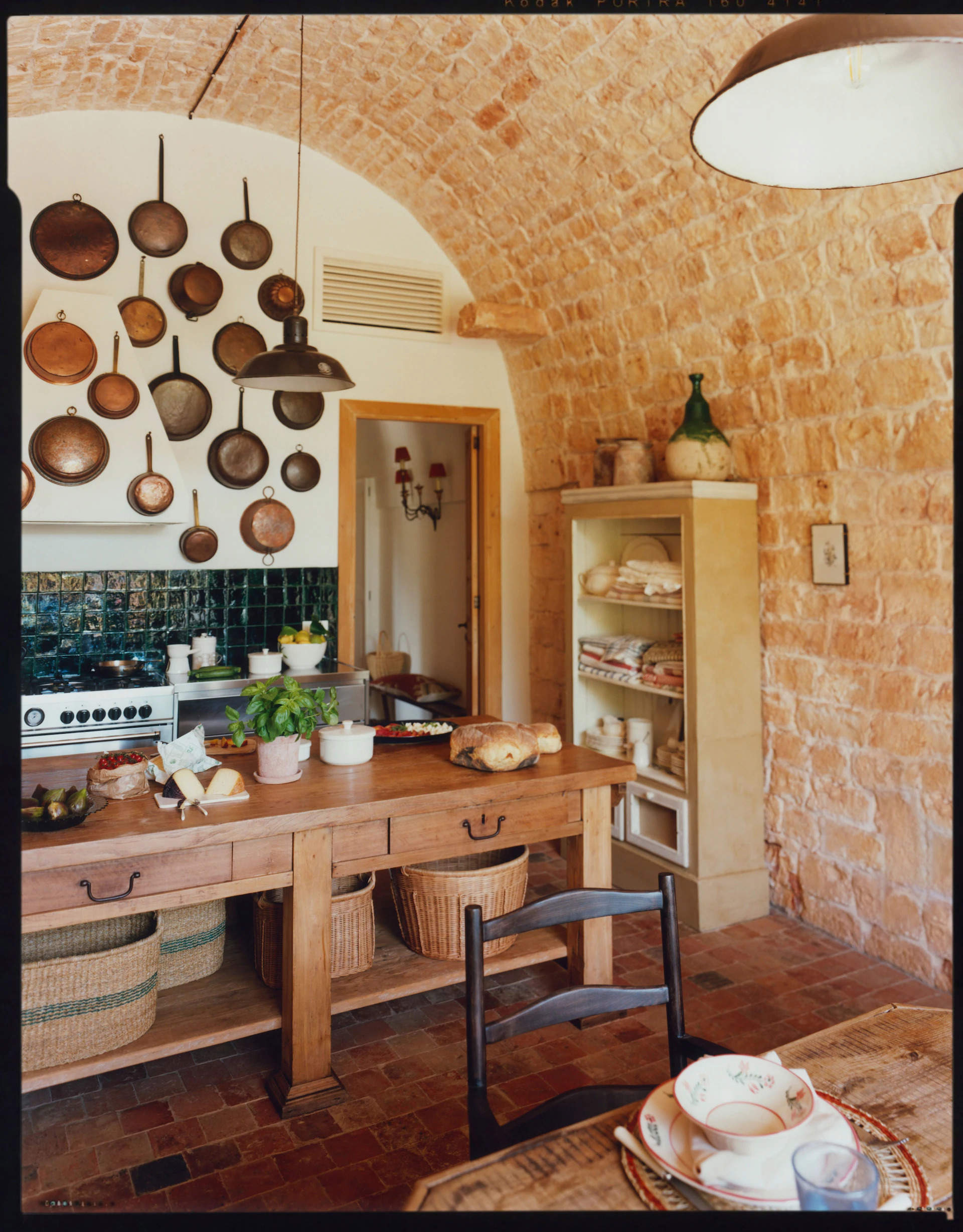 Cocina rústica con paredes de piedra y cazuelas de cobre