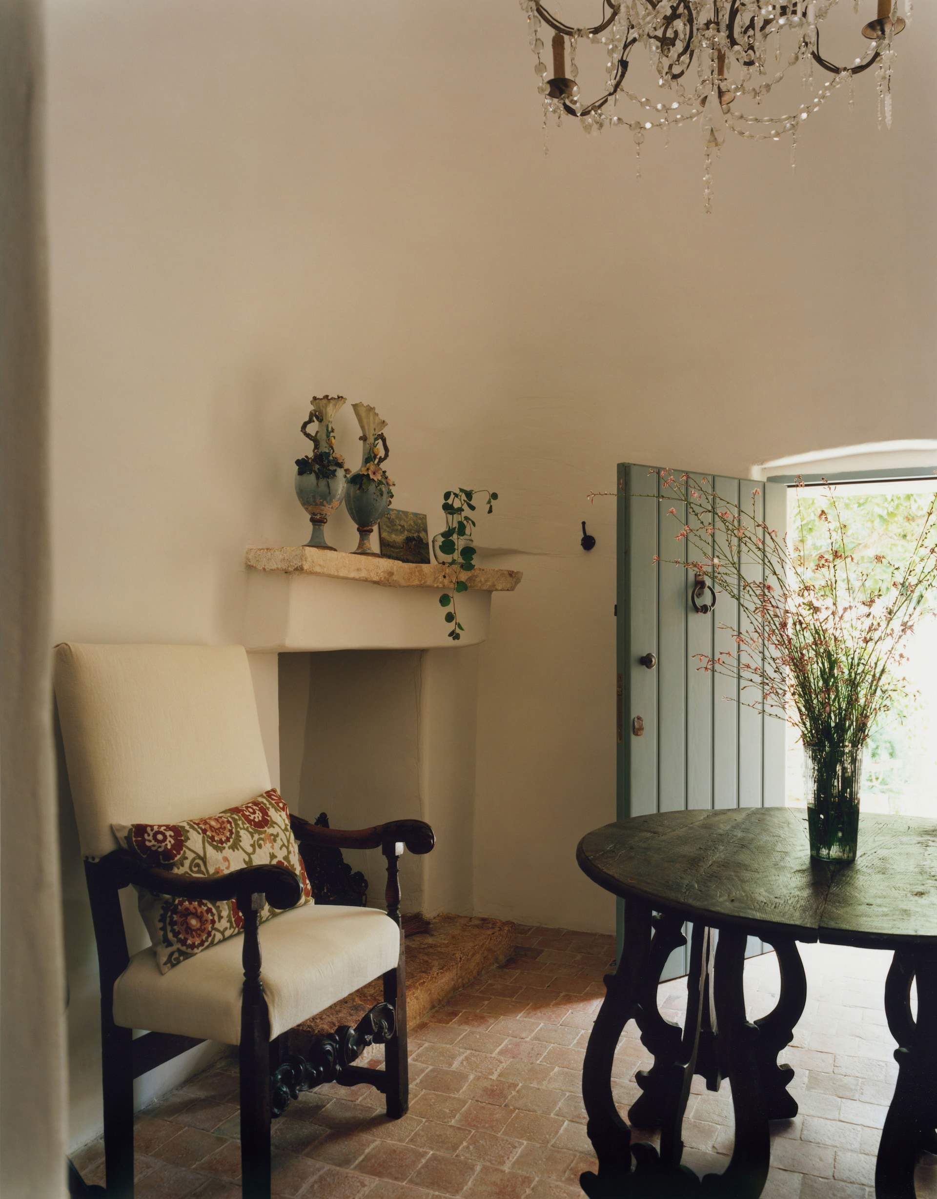 Entrada de la casa con mesa de madera y silla tapizada.