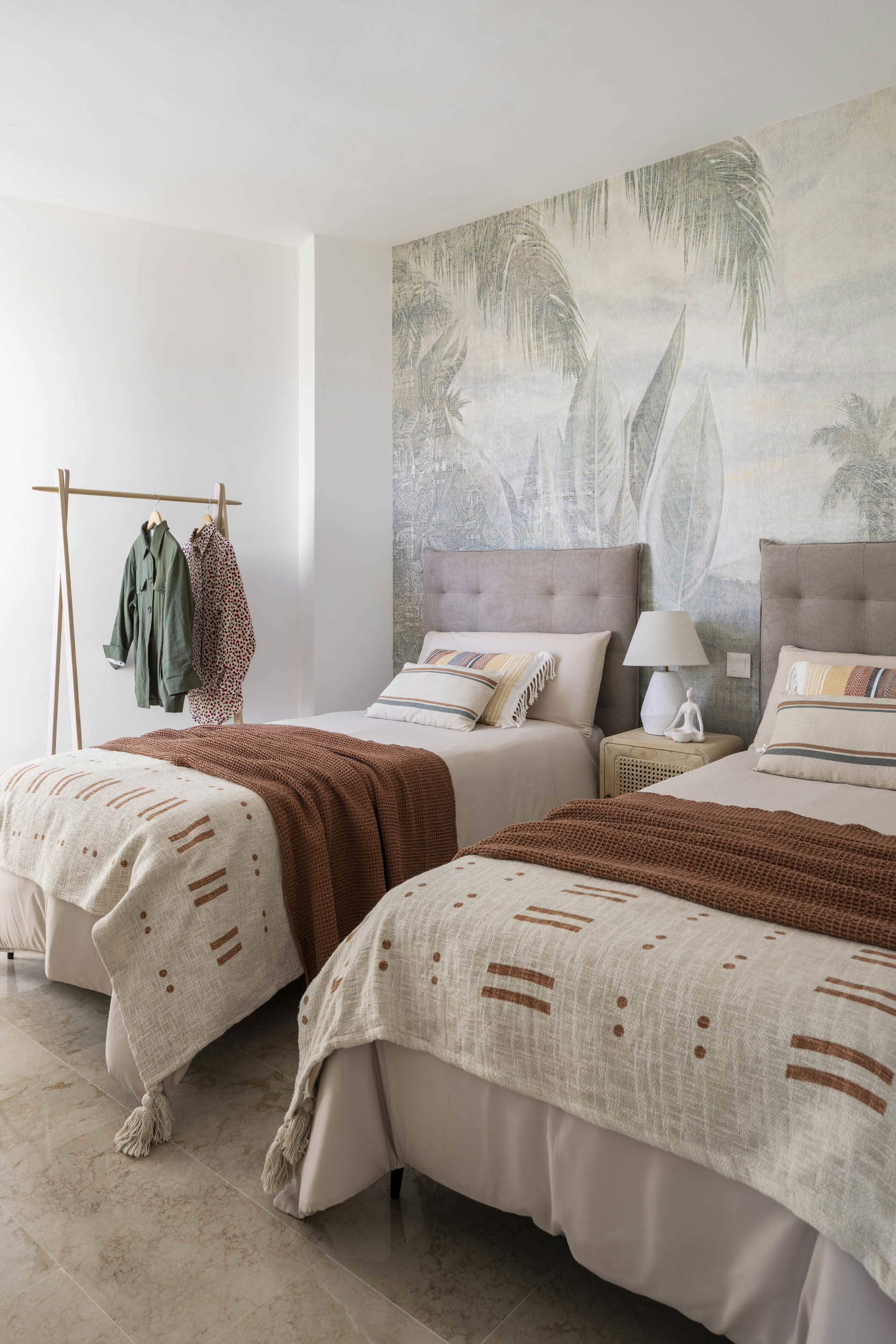Habitación de camas individuales, cabeceros tapizados y papel pintado.