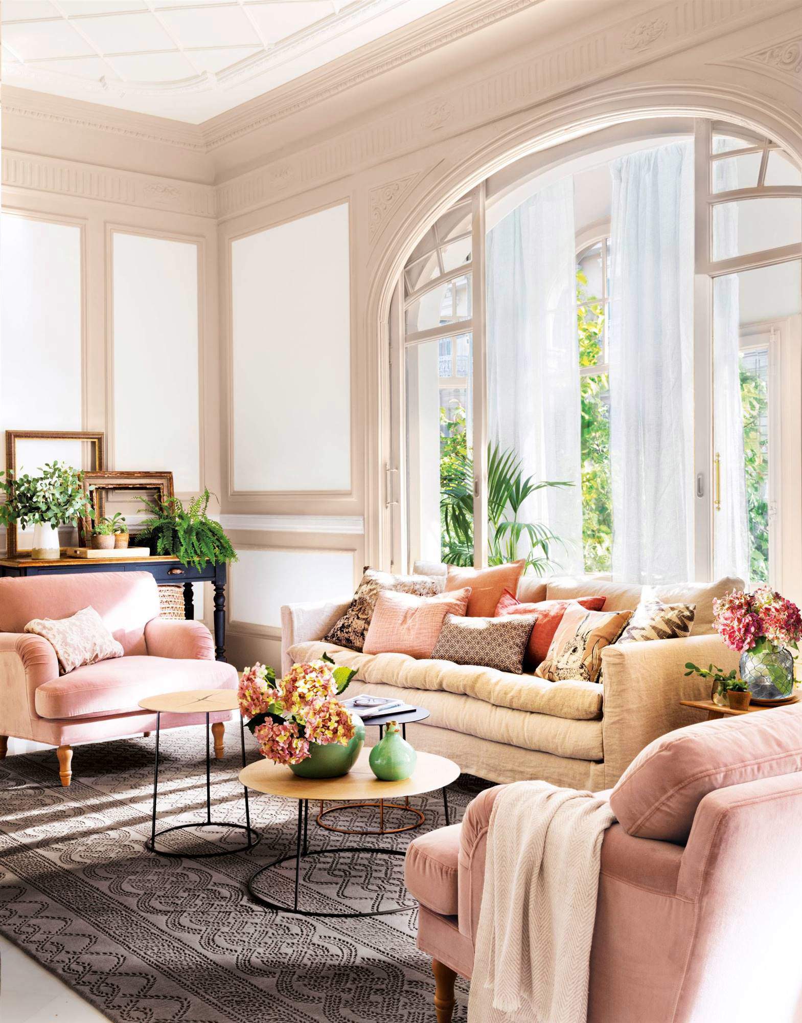 Salón decorado con sofás rosas y gran ventanal de semi arco.