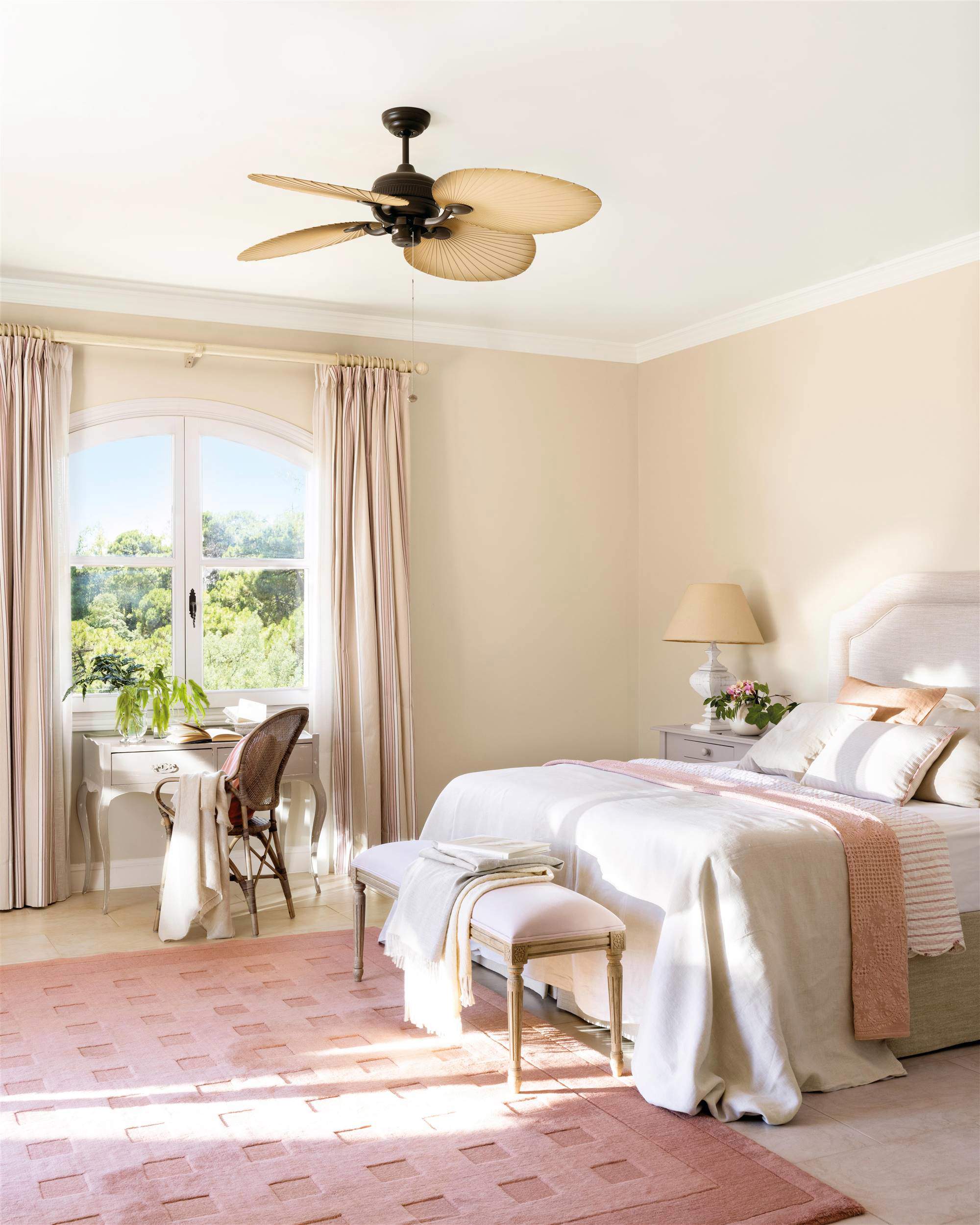 Dormitorio con escritorio en ventana y alfombra rosa.