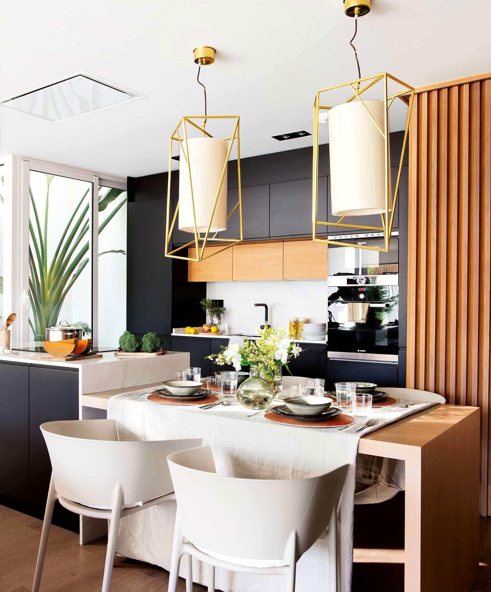 Cocina moderna con barra y office en negro y elementos dorados.