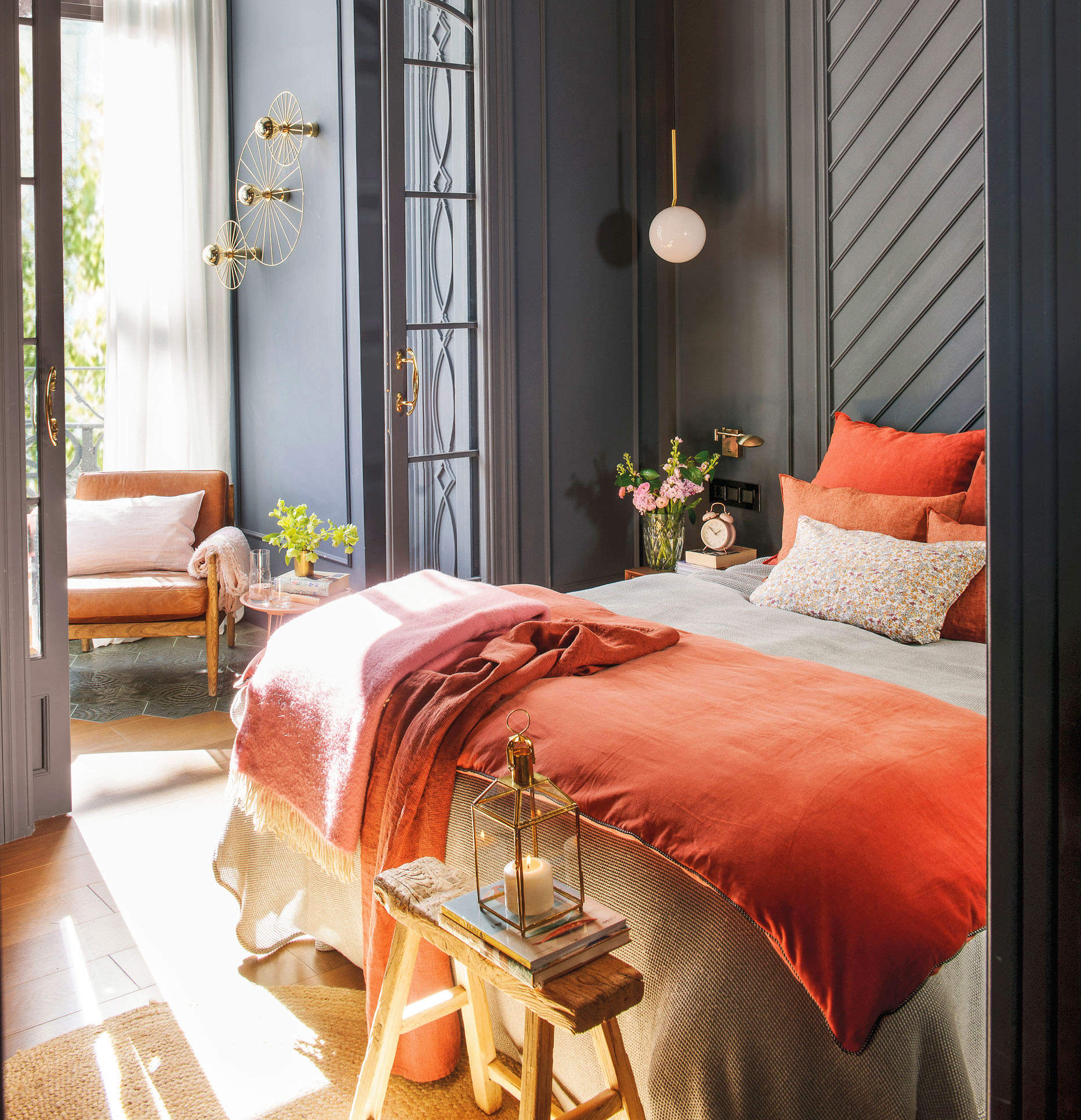 Dormitorio con ropa de cama en color coral y paredes con molduras en gris oscuro .
