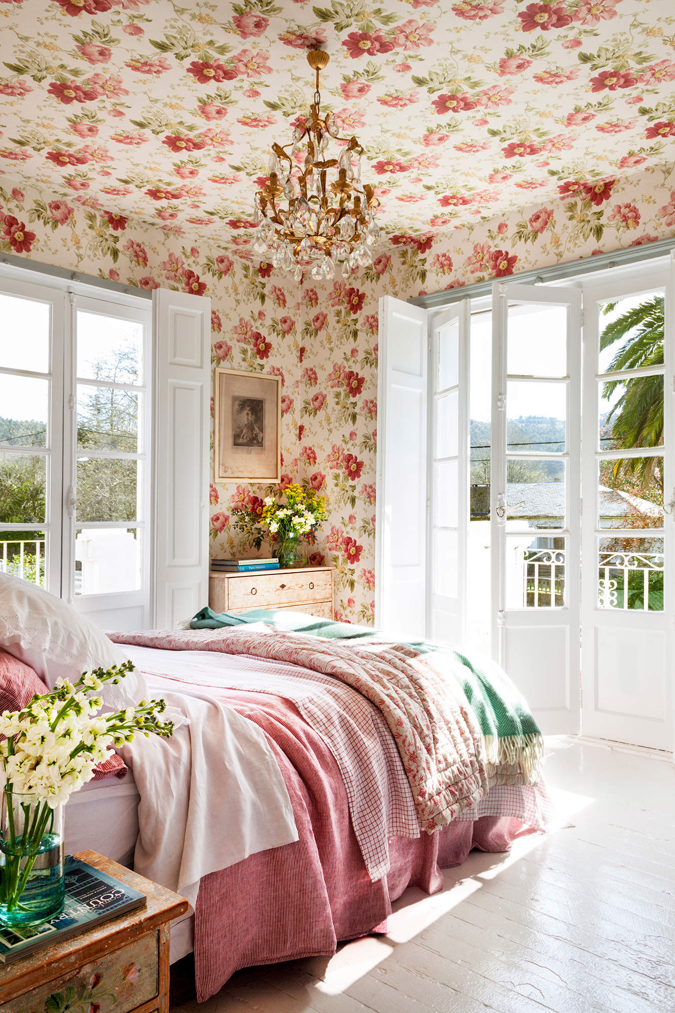 Dormitorio con ventanales y papel pintado de flores en techo y paredes.