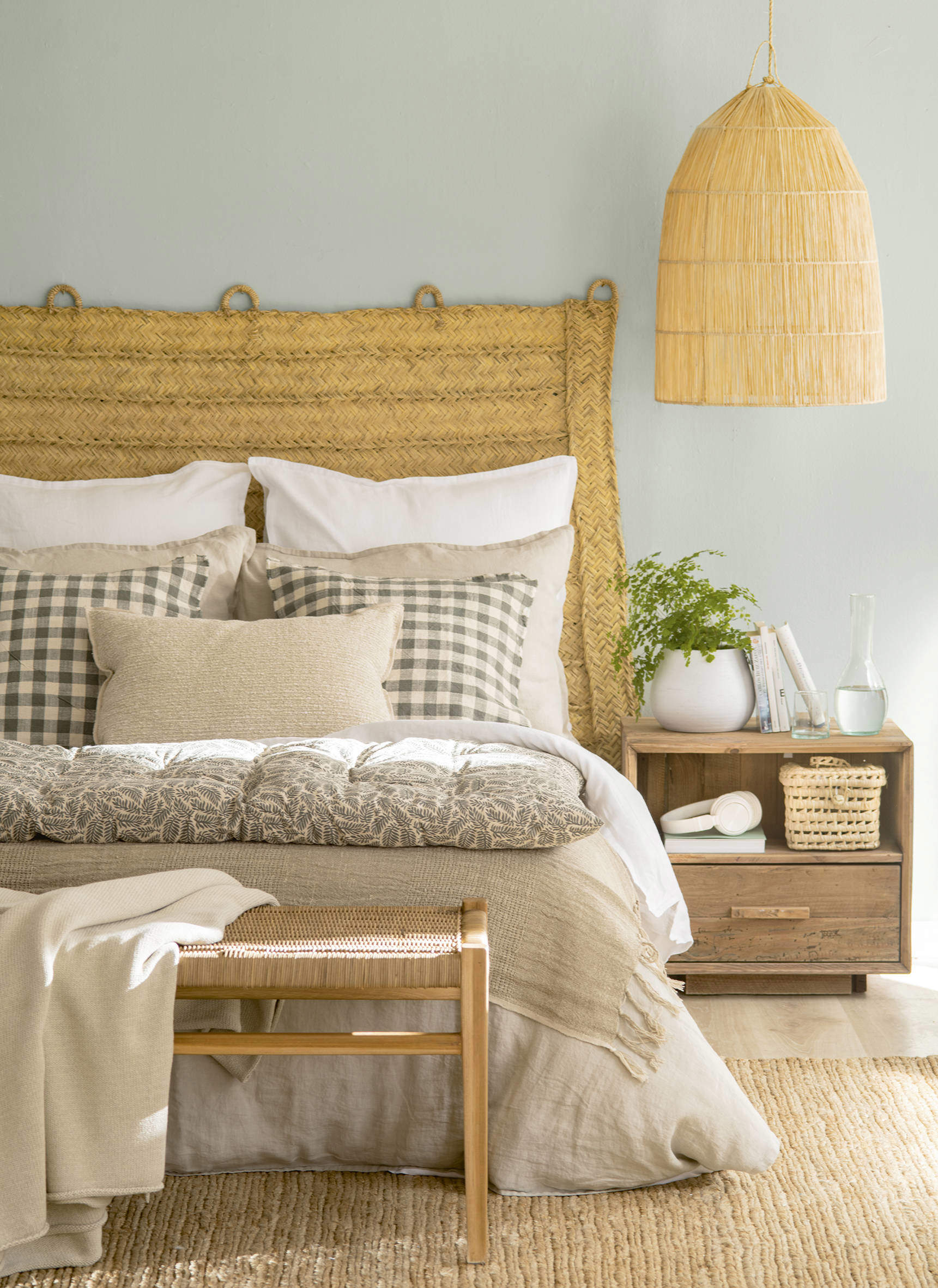 Dormitorio de estilo rústico con cabecero y lámpara en fibras naturales.