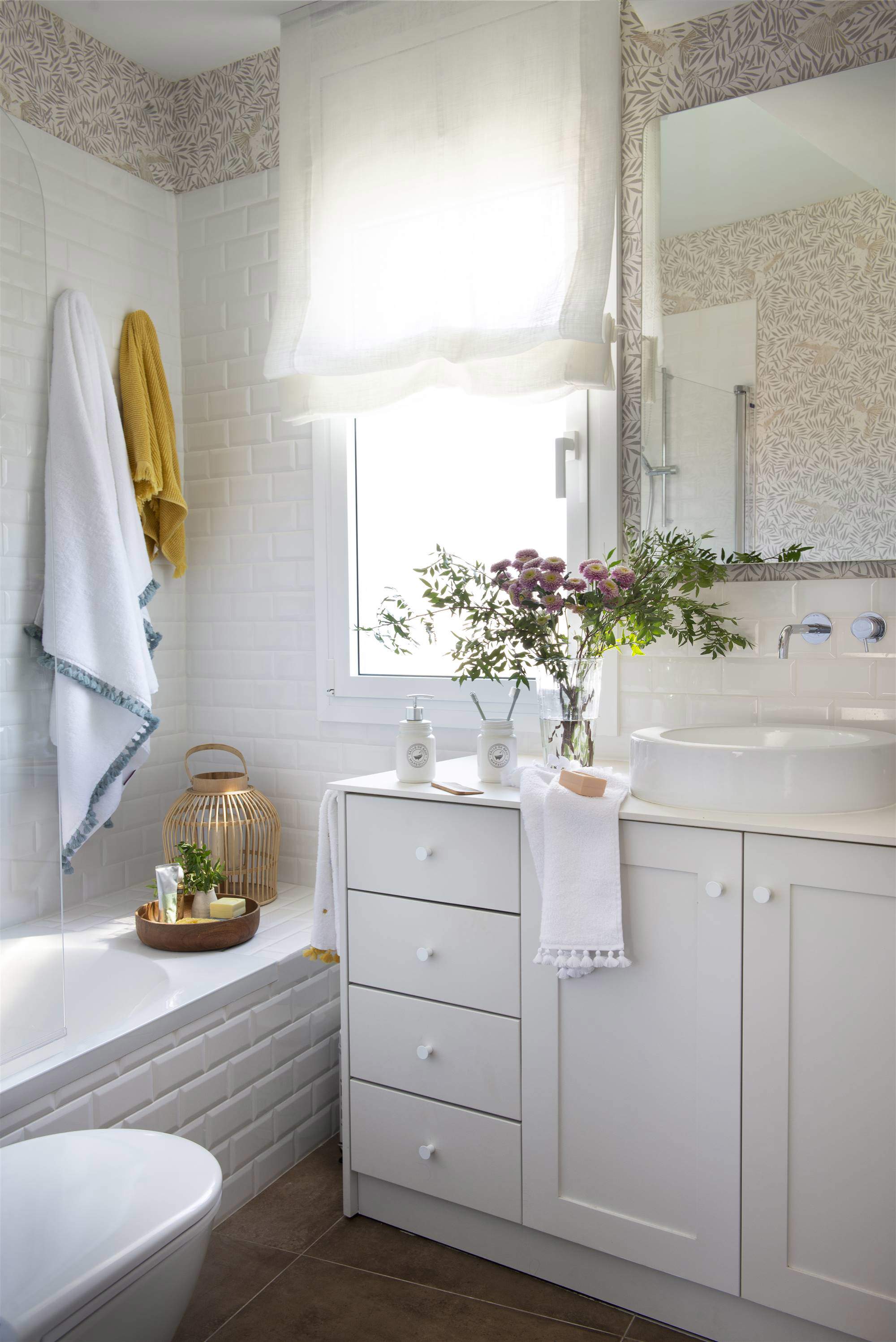 Baño con mueble blanco y papel pintado y azulejos.