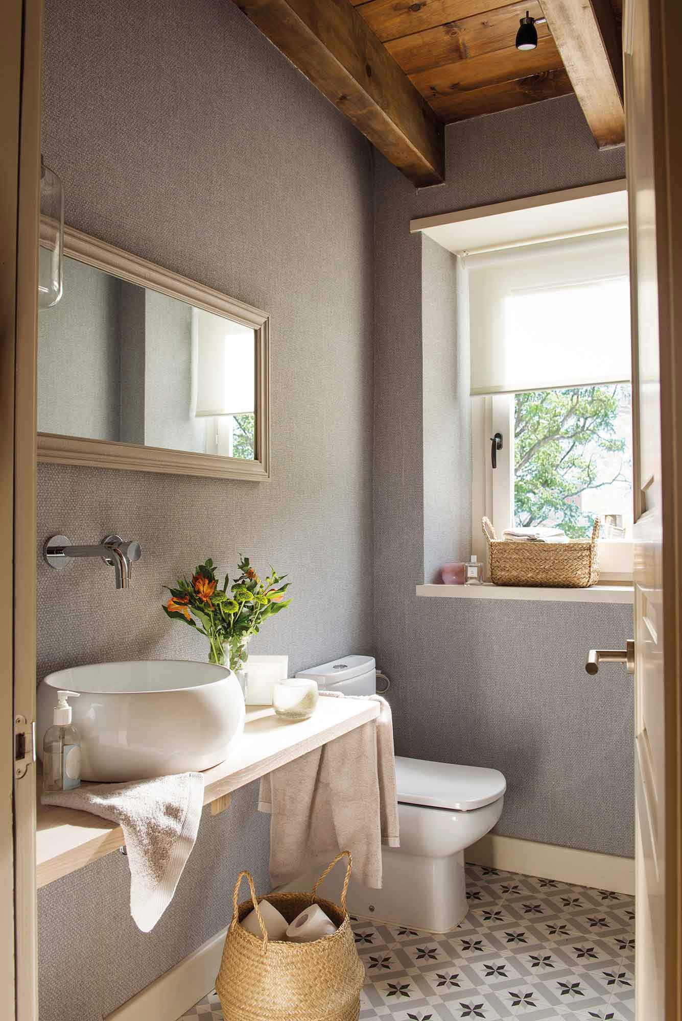 Baño con frente de papel pintado tejido en color gris y balda de madera como mueble de lavabo.