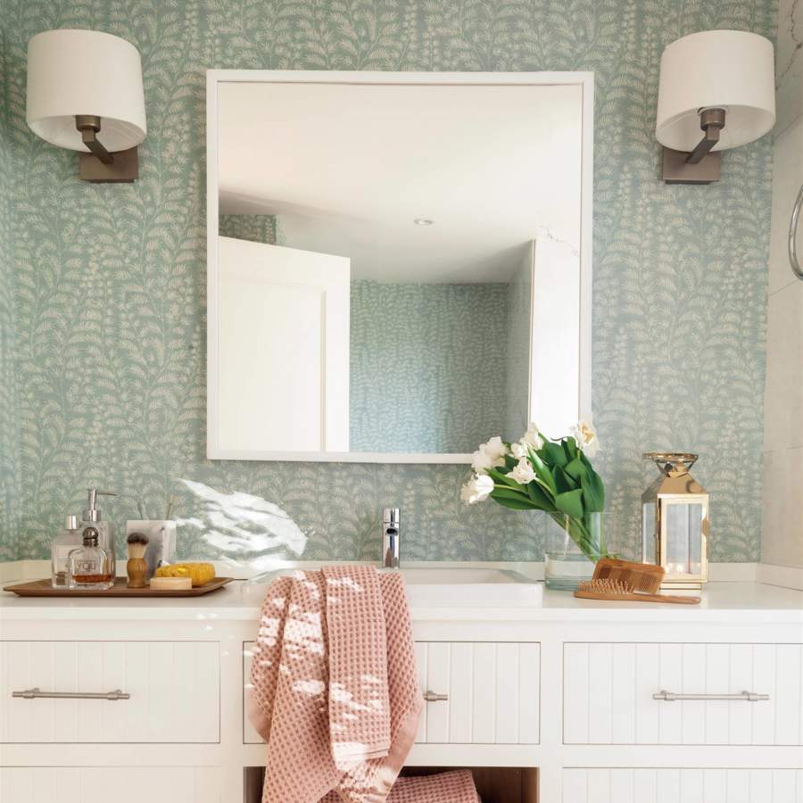 Baño con frente de papel pintado floral y mueble blanco.
