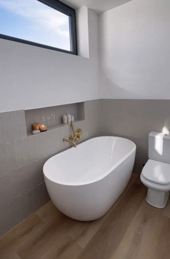 Baño moderno con bañera exenta y arrimadero de azulejos.
