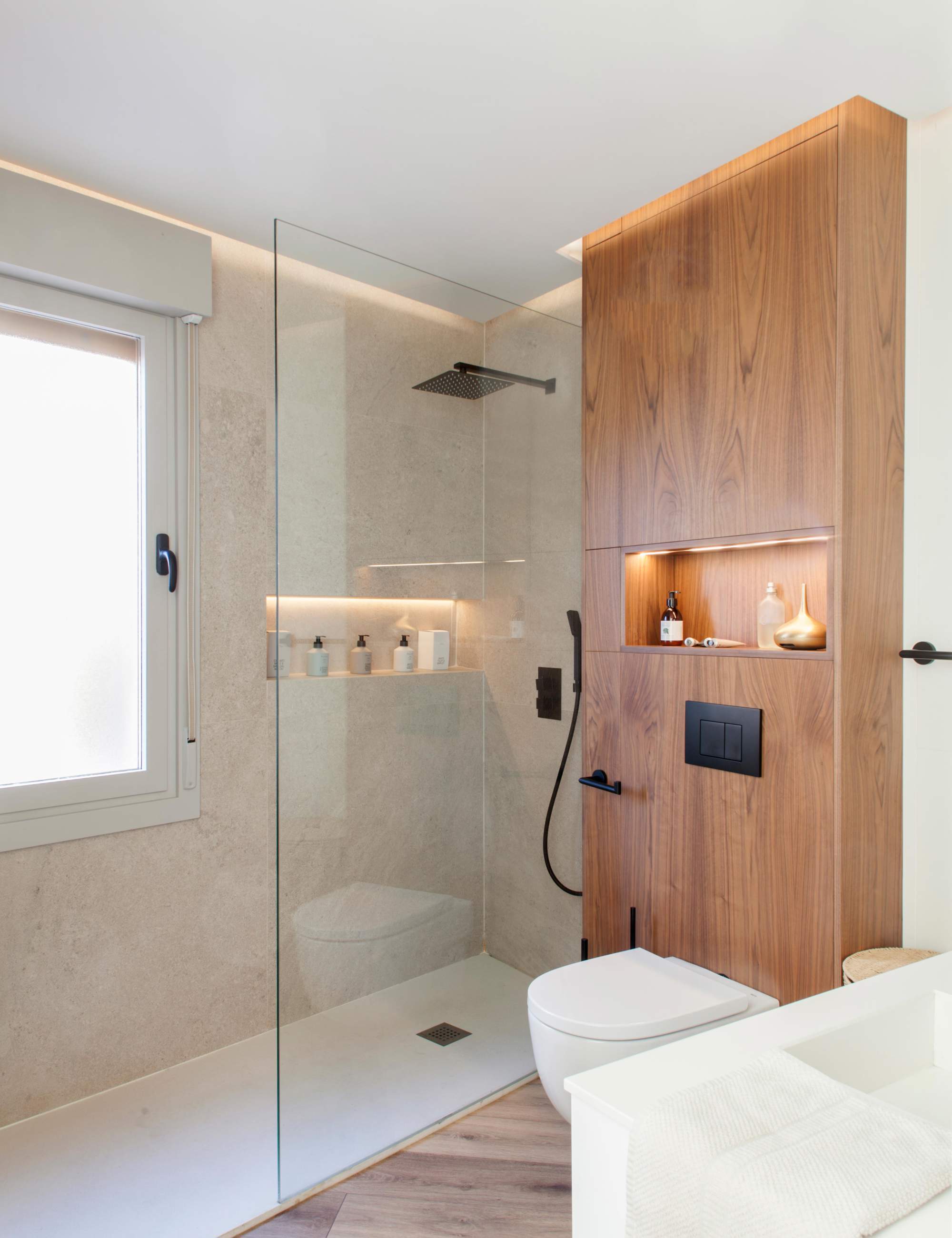 Baño moderno con ducha y mueble encima del wc.