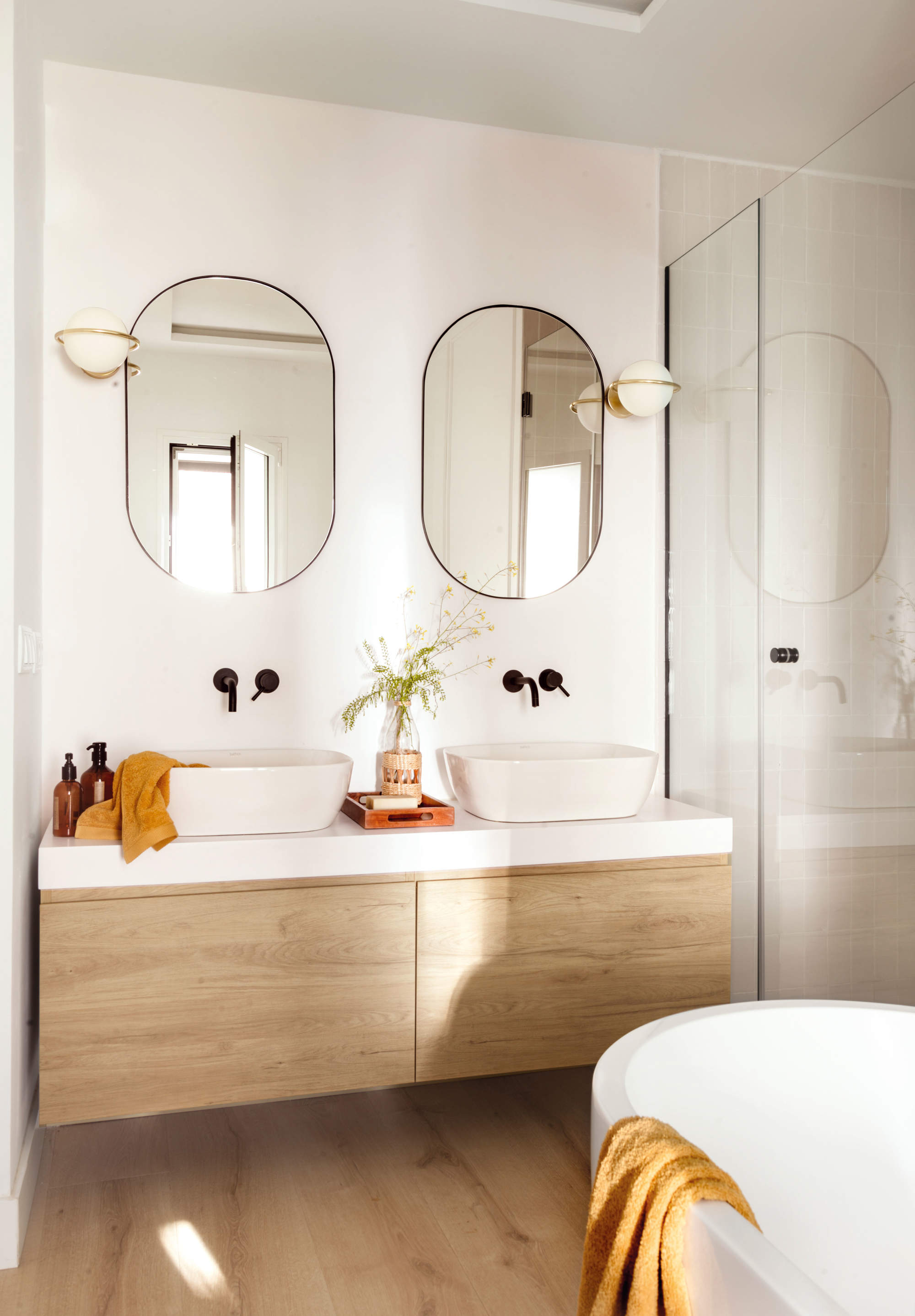 Baño con mueble volado y espejos ovalados.