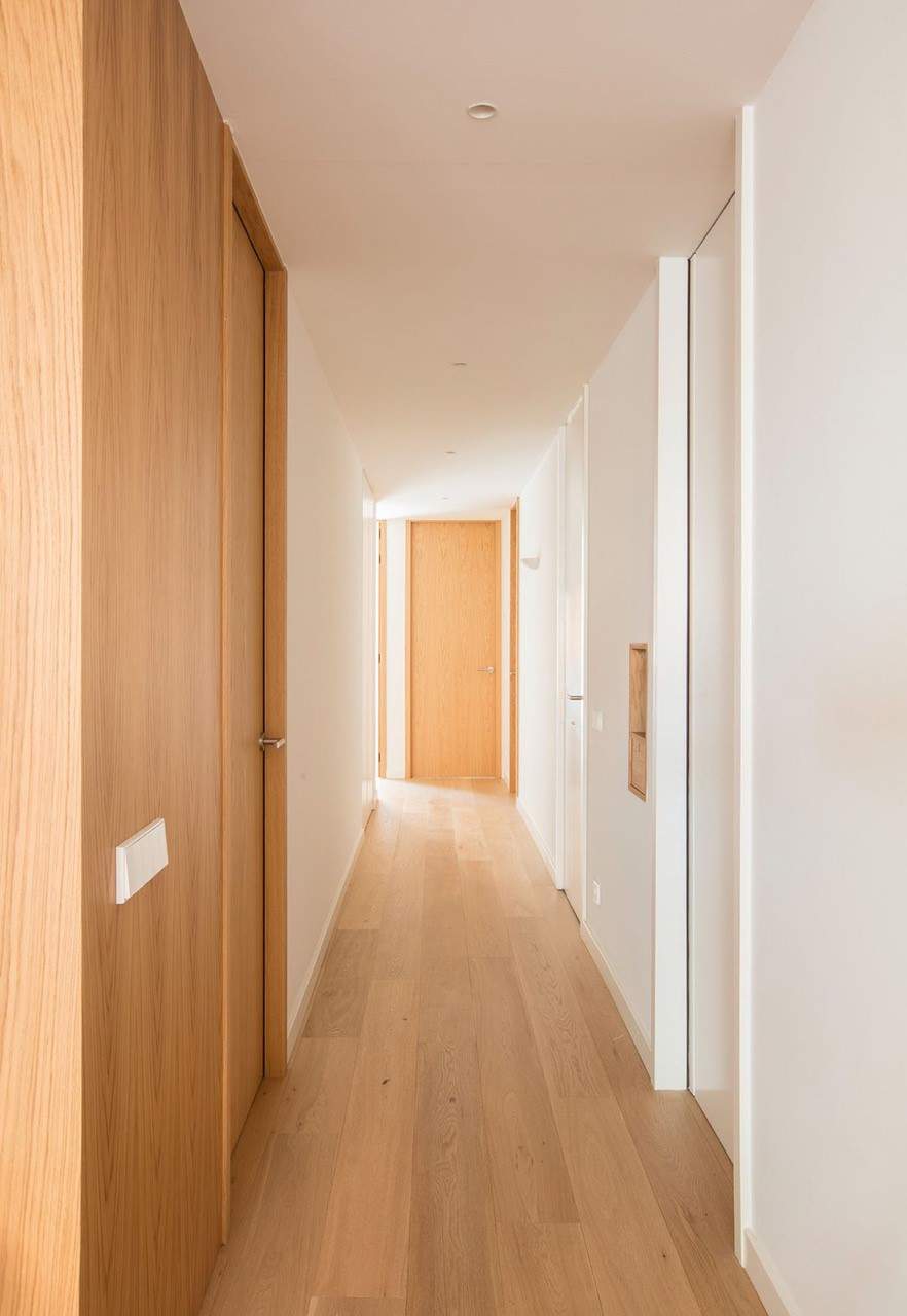 Un pasillo con puertas que van de suelo a techo, de madera de roble.