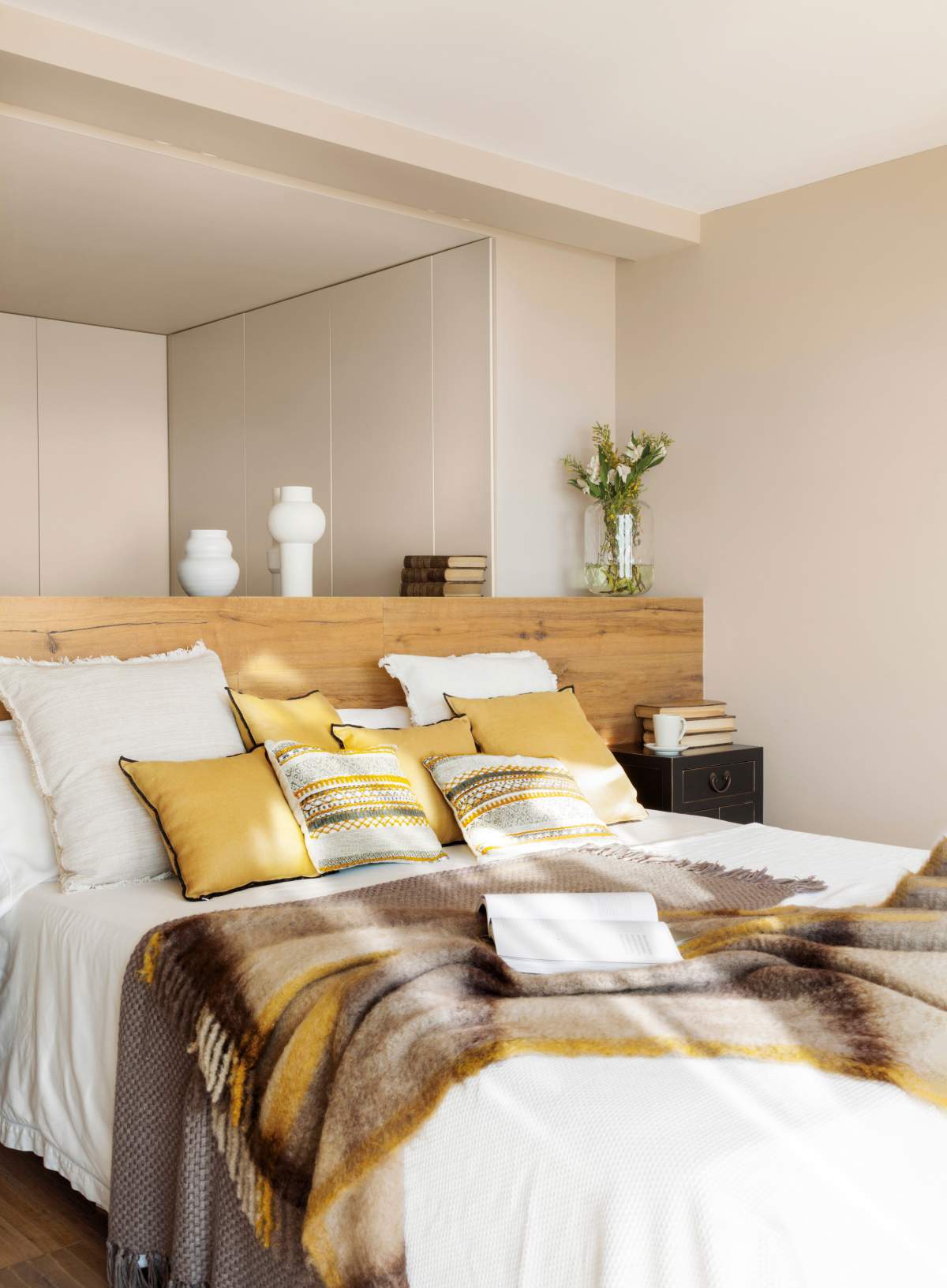 Dormitorio con cojines en tonos mostaza y marrones.
