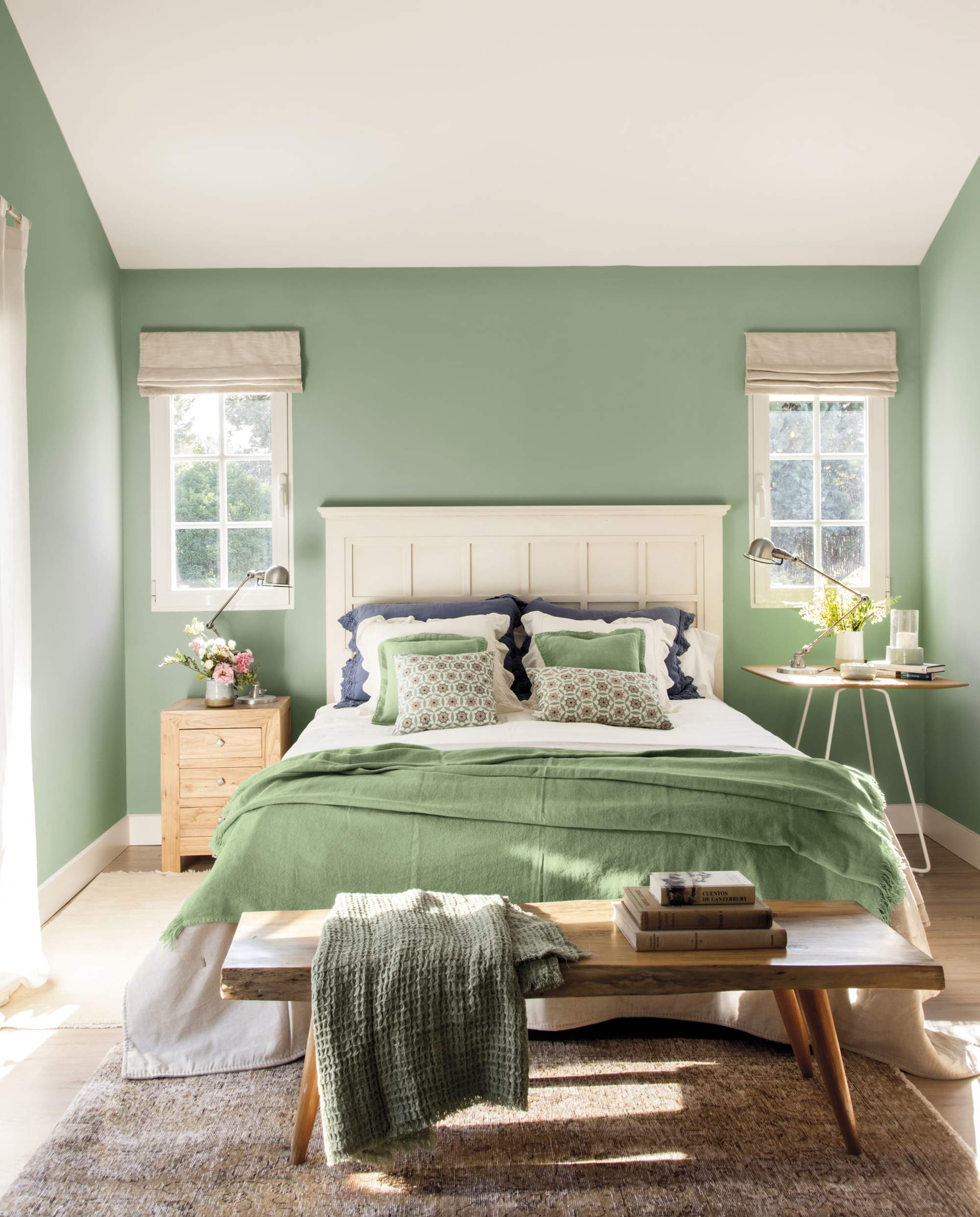 Cabecero blanco con friso decorativo en habitación de paredes verdes.