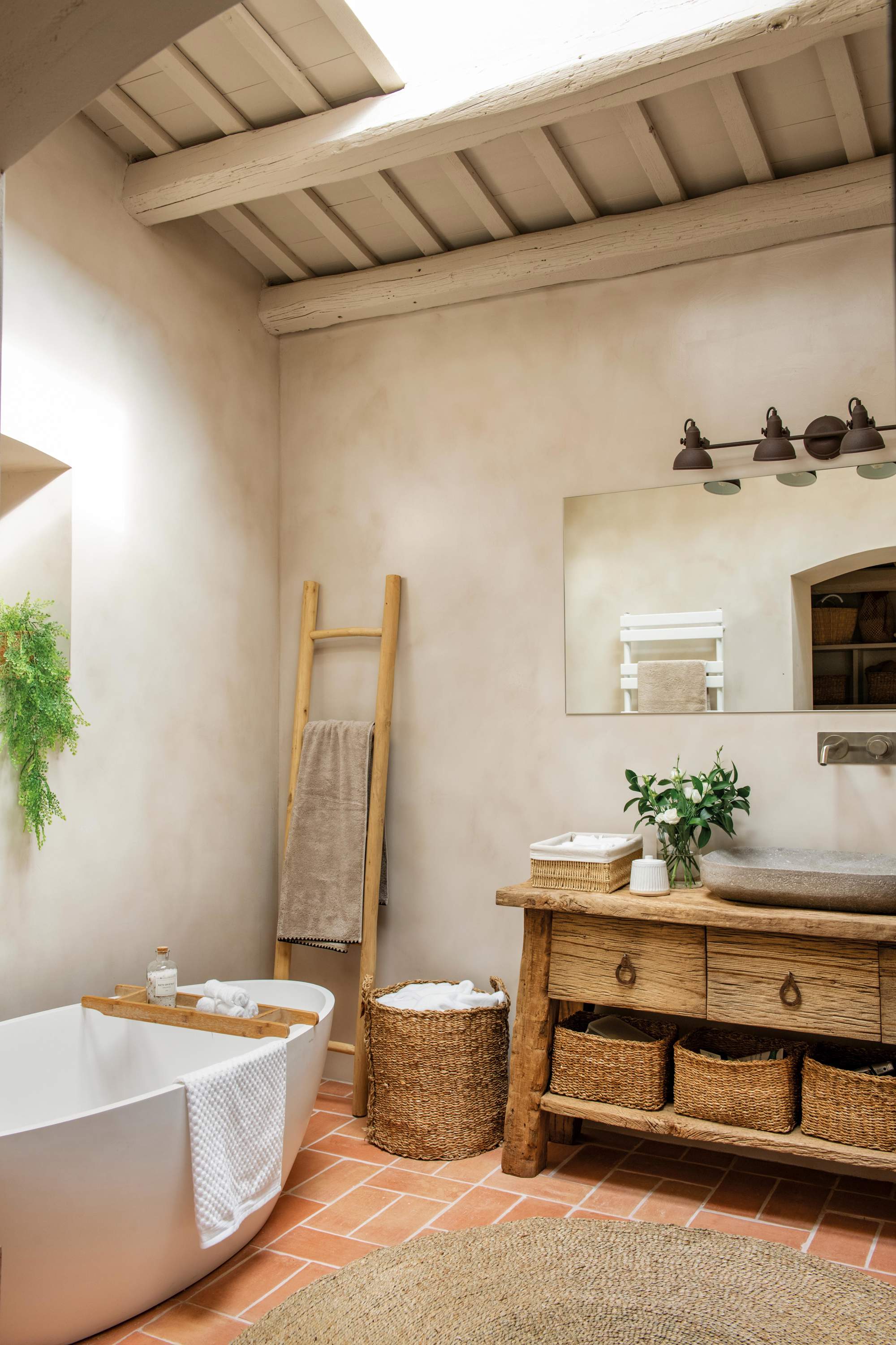 Baño en color arena con bañera, mueble y escalera toallero de madera.