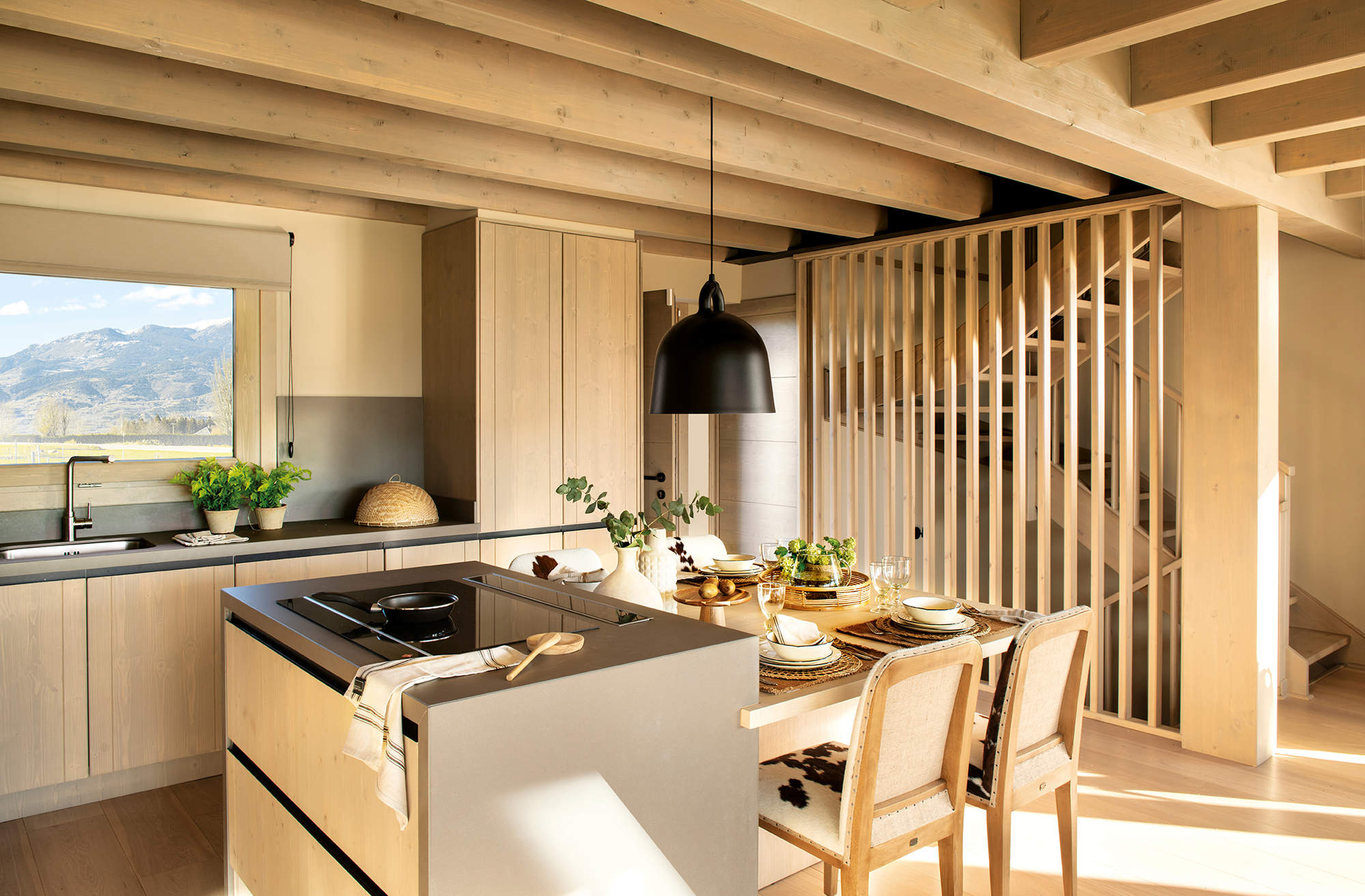 Cocina abierta con muebles en madera e isla con mesa adosad.