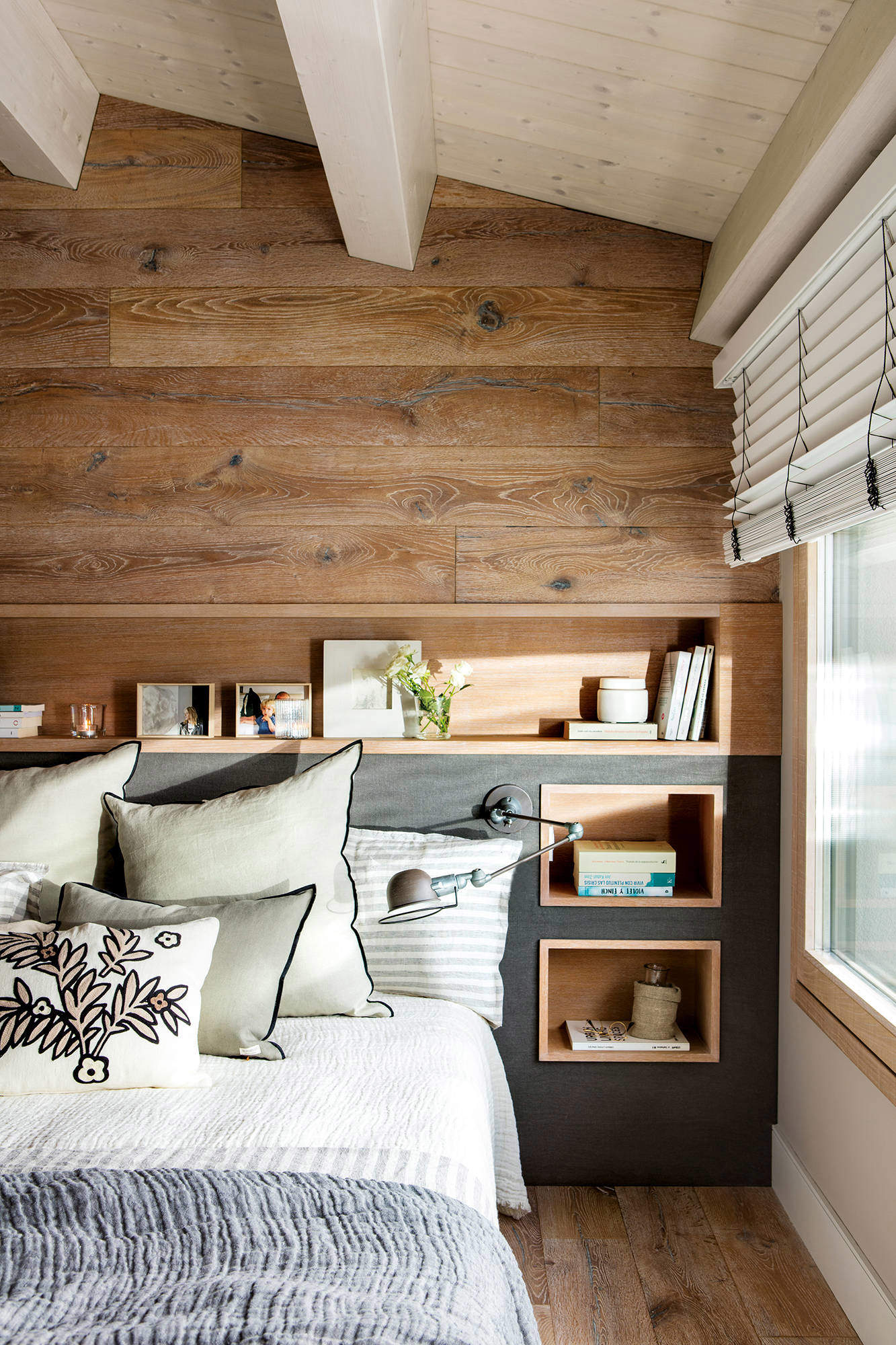 Dormitorio de madera con cabecero de obra y flexo articulado.