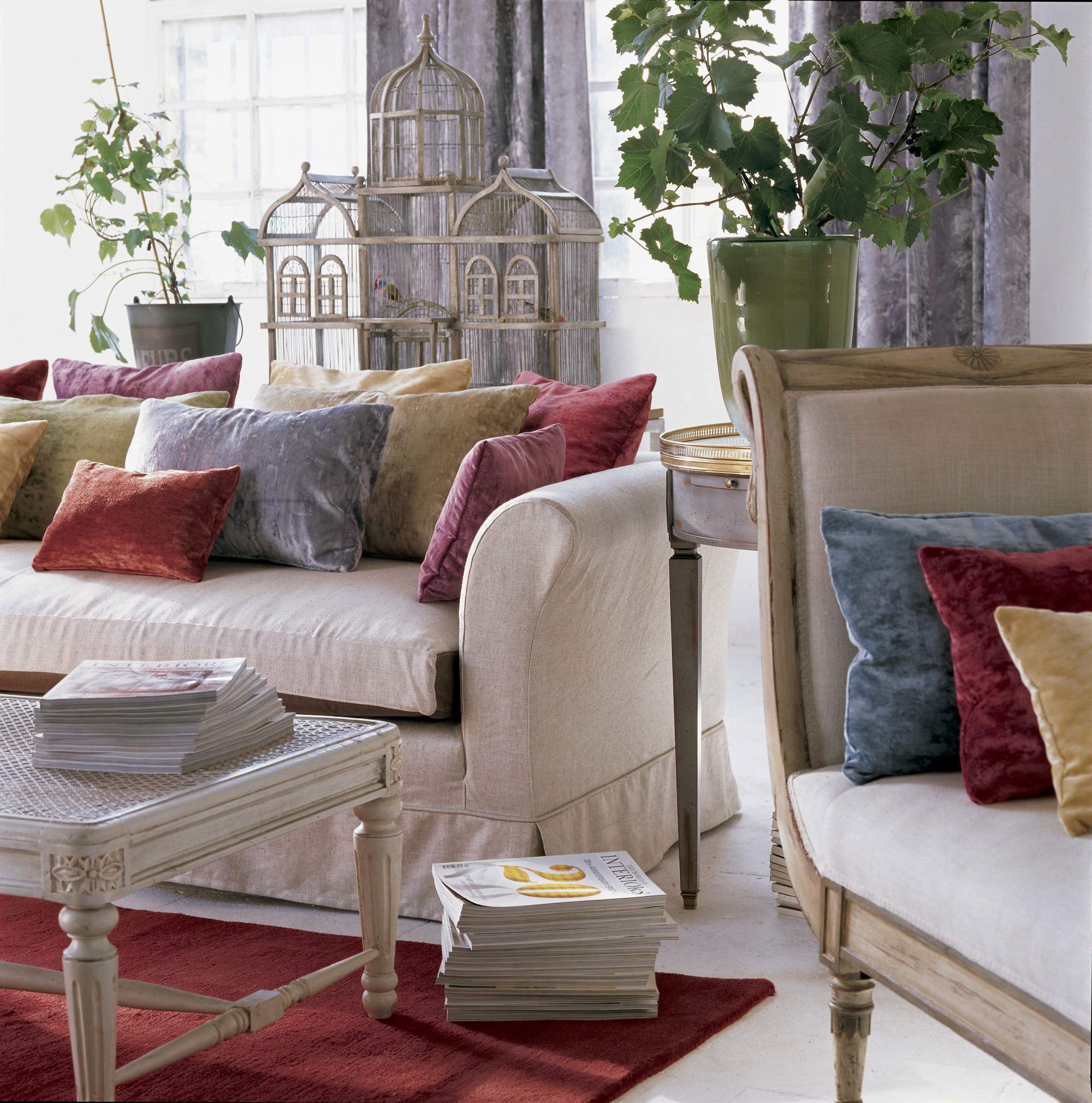 Salón con sofá blanco, alfombra granate y cojines de colores