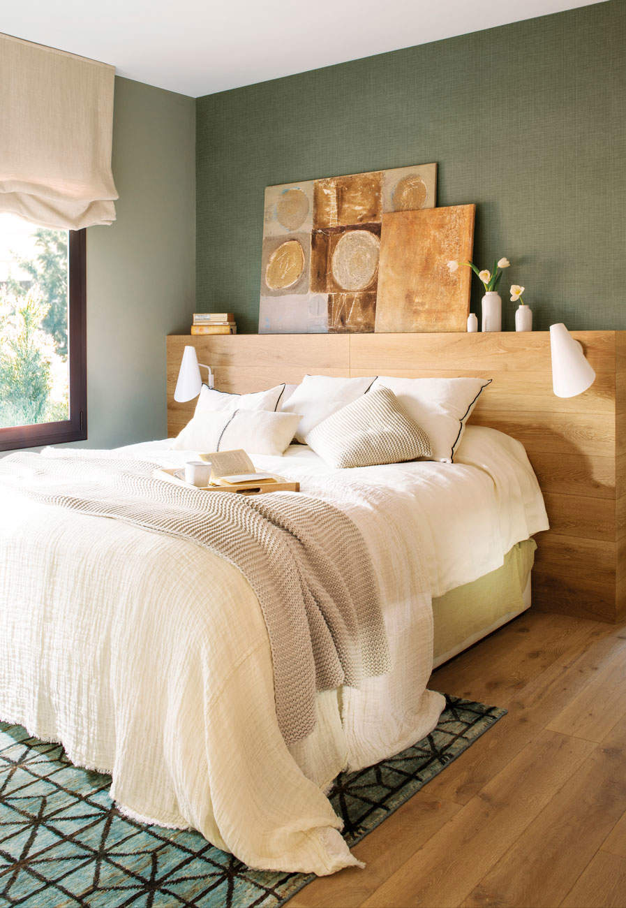Dormitorio con pared verde y cabecero de madera.