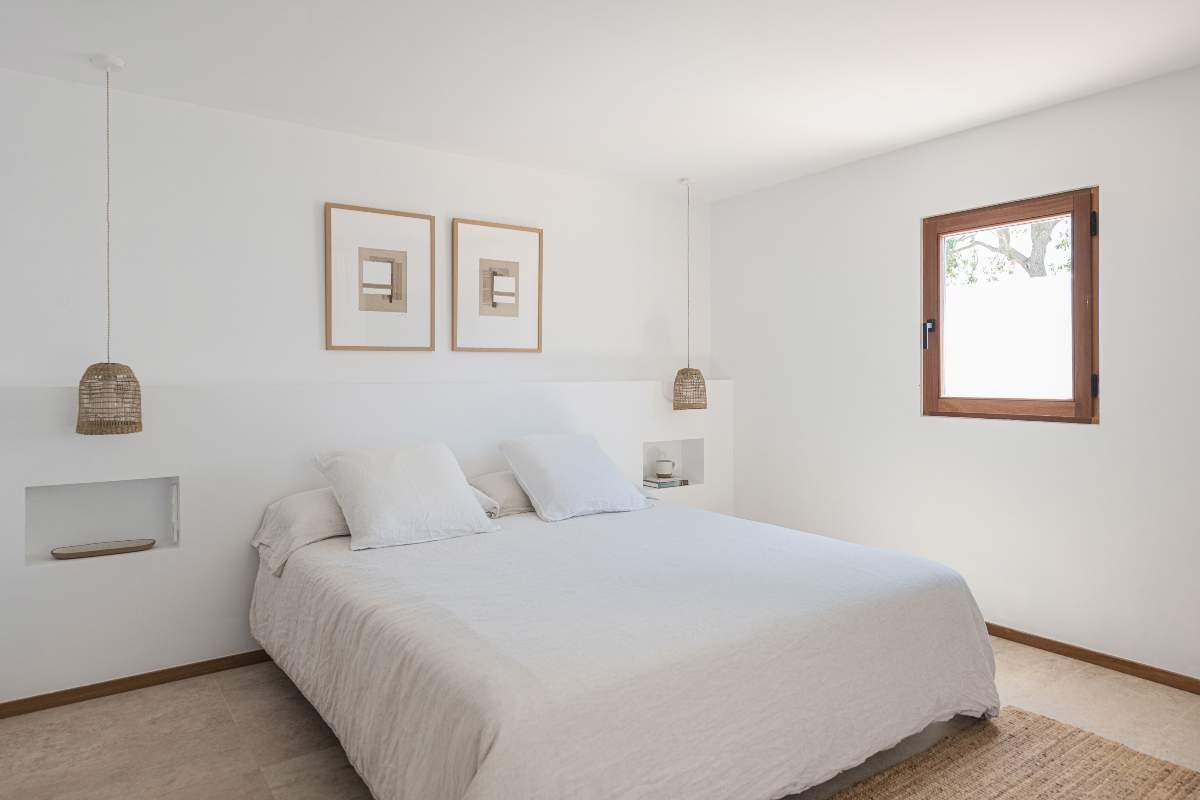 Un dormitorio en tonos blancos y fibras naturales.