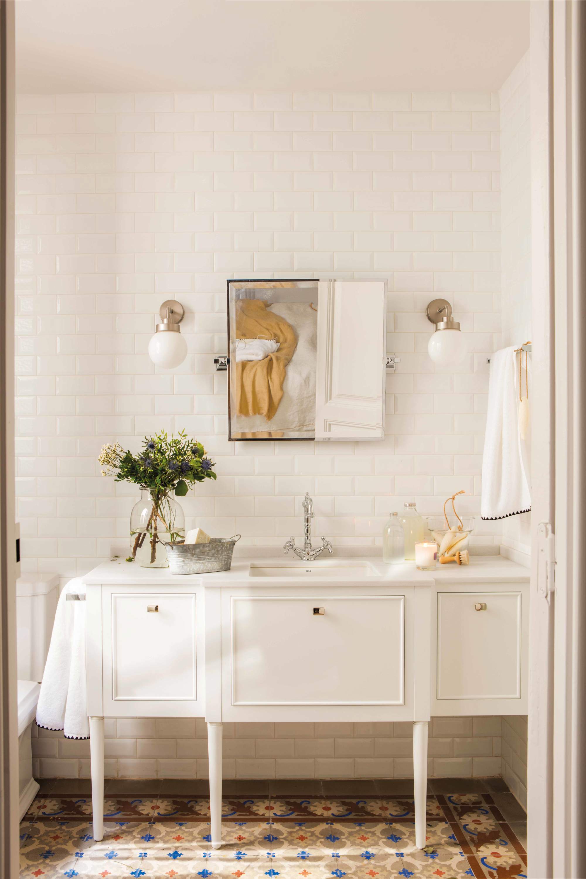 Baño con mueble bajolavabo con puertas lacado en blanco, espejo, apliques globo, azulejos metro y suelo hidraúlico