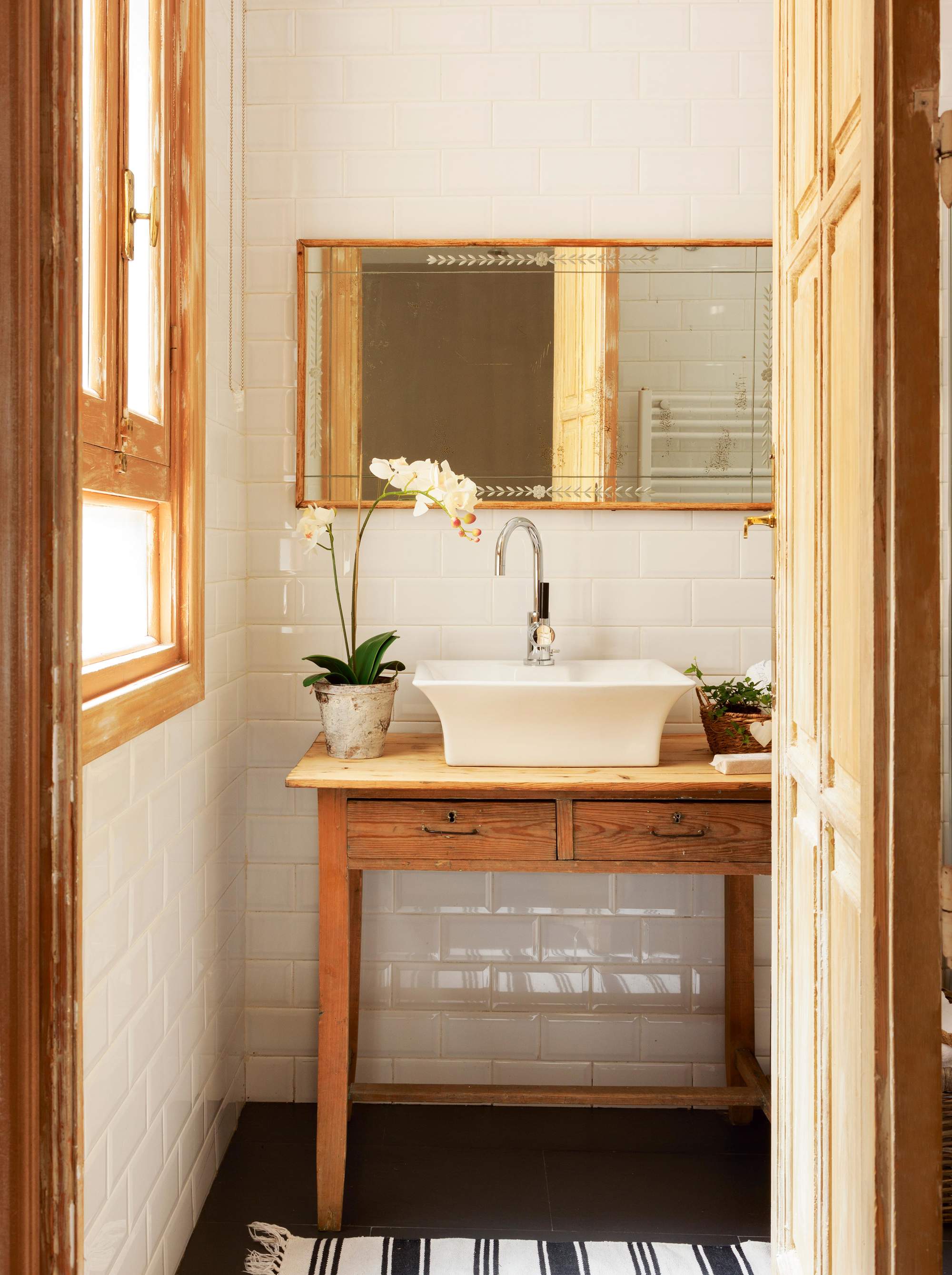 Baño con mesa tocinera de madera con cajones, lavabo exento, espejo y azulejos metro