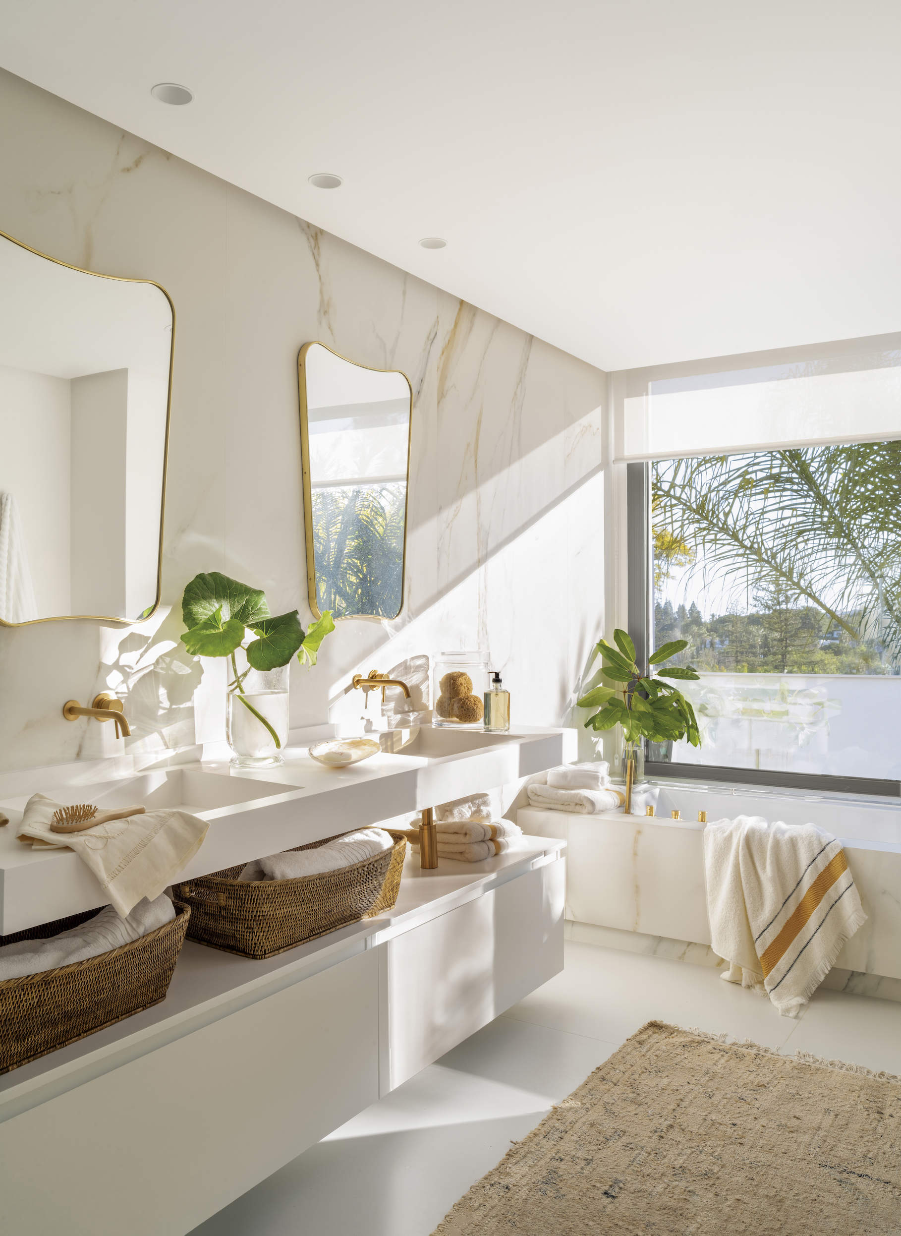 Baño moderno con mueble blanco y paredes de mármol.