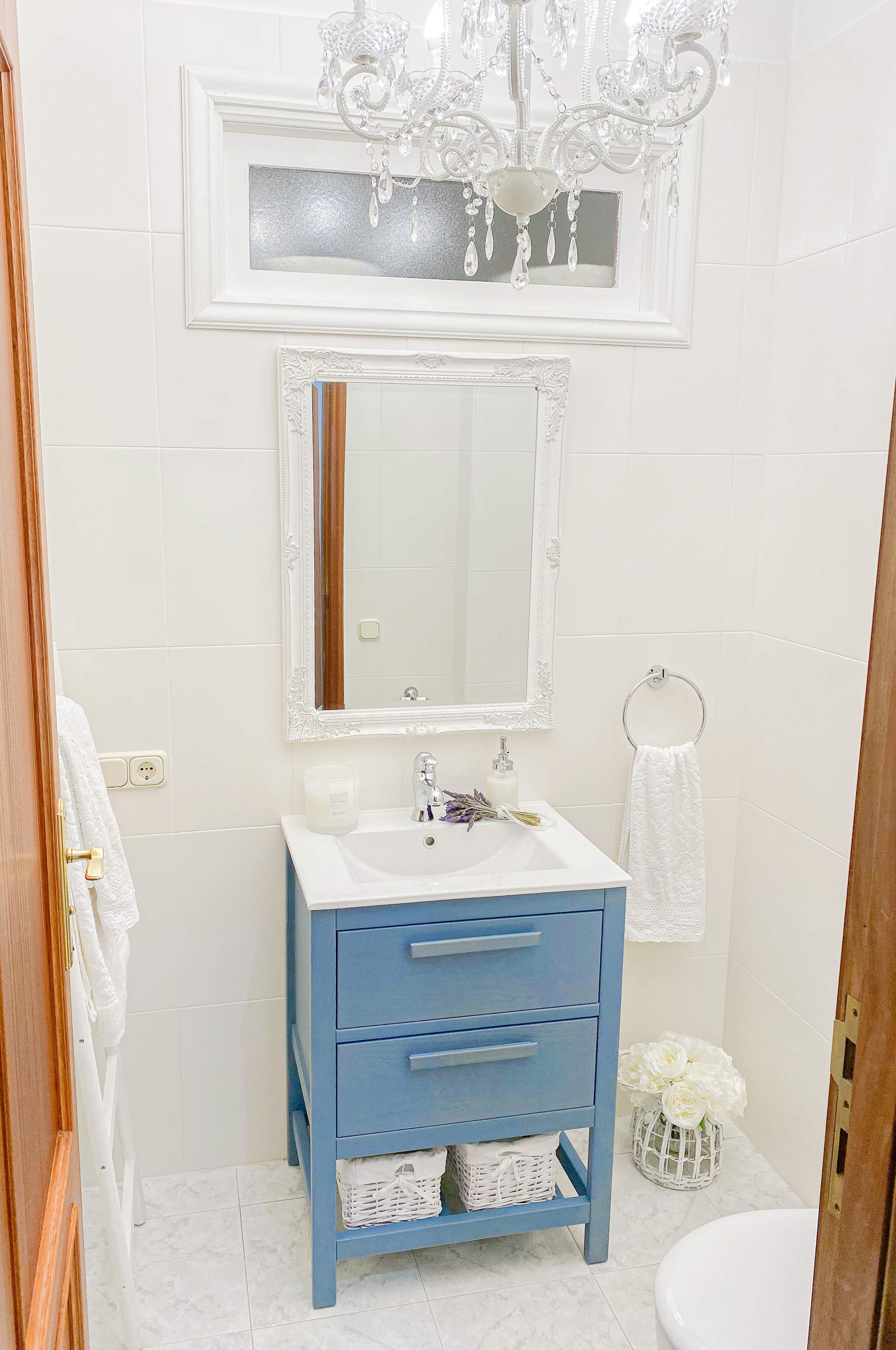 Aseo en tonos blancos con mueble de lavabo en azul.