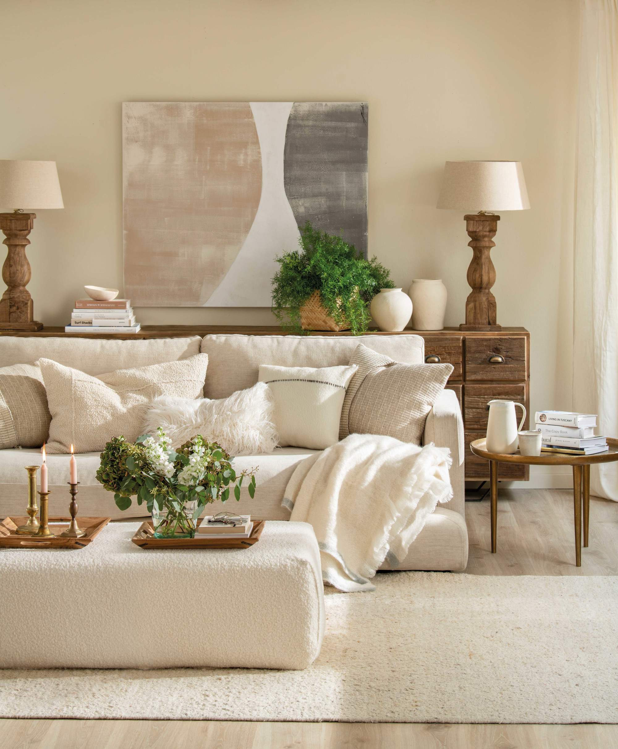 Salón con sofá crudo, puf a modo de mesa de centro, cuadro y alfombra clara