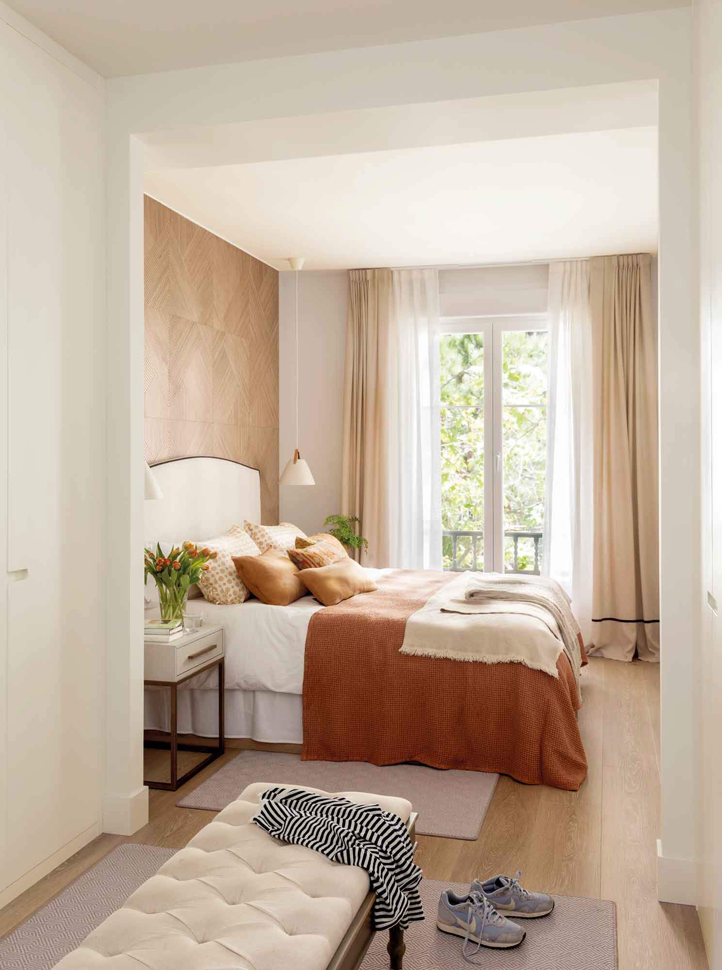 Dormitorio con vestidor y revestimiento de madera en el cabecero.