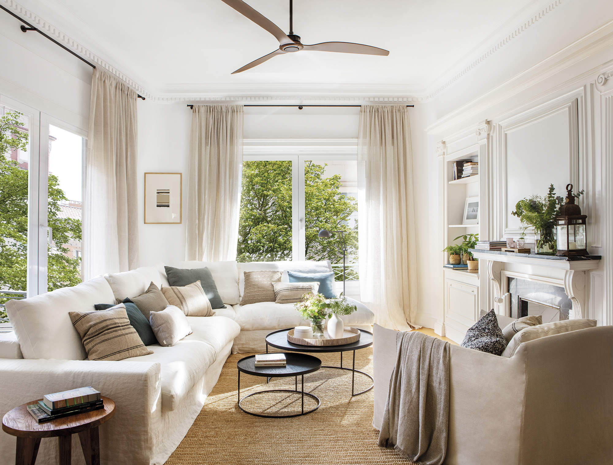 Salón con sofá blanco, alfombra de fibras, butaca beige y molduras.