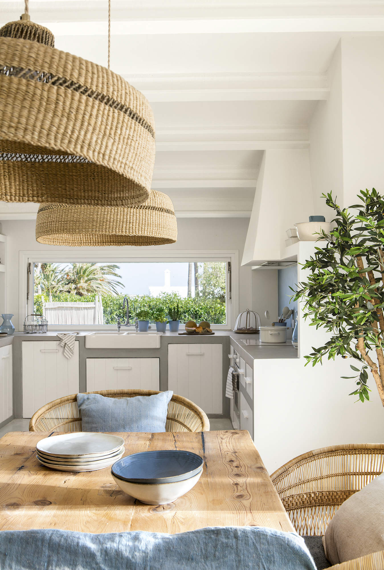 Cocina de microcemento y puertas de madera con mesa rústica y lámpara de fibras