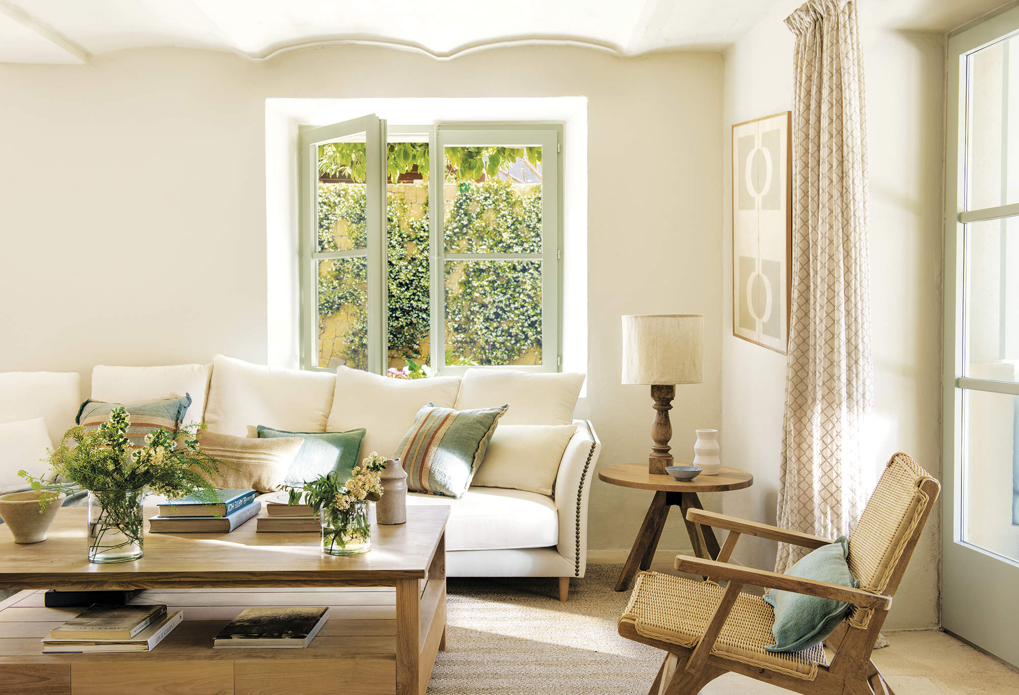 Salón luminoso con sofá blanco, cortinas estampadas y mesa de madera