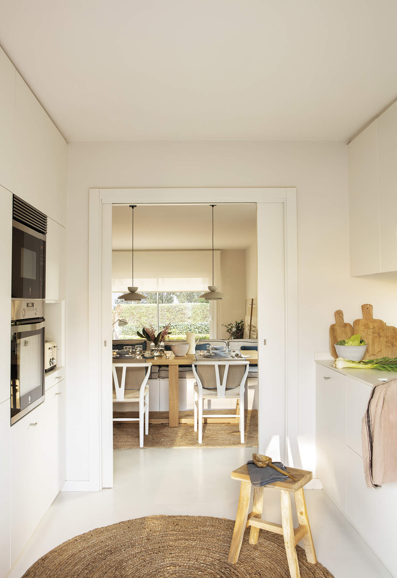 Cocina blanca con puertas correderas, suelo de microcemento y alfombra de fibras