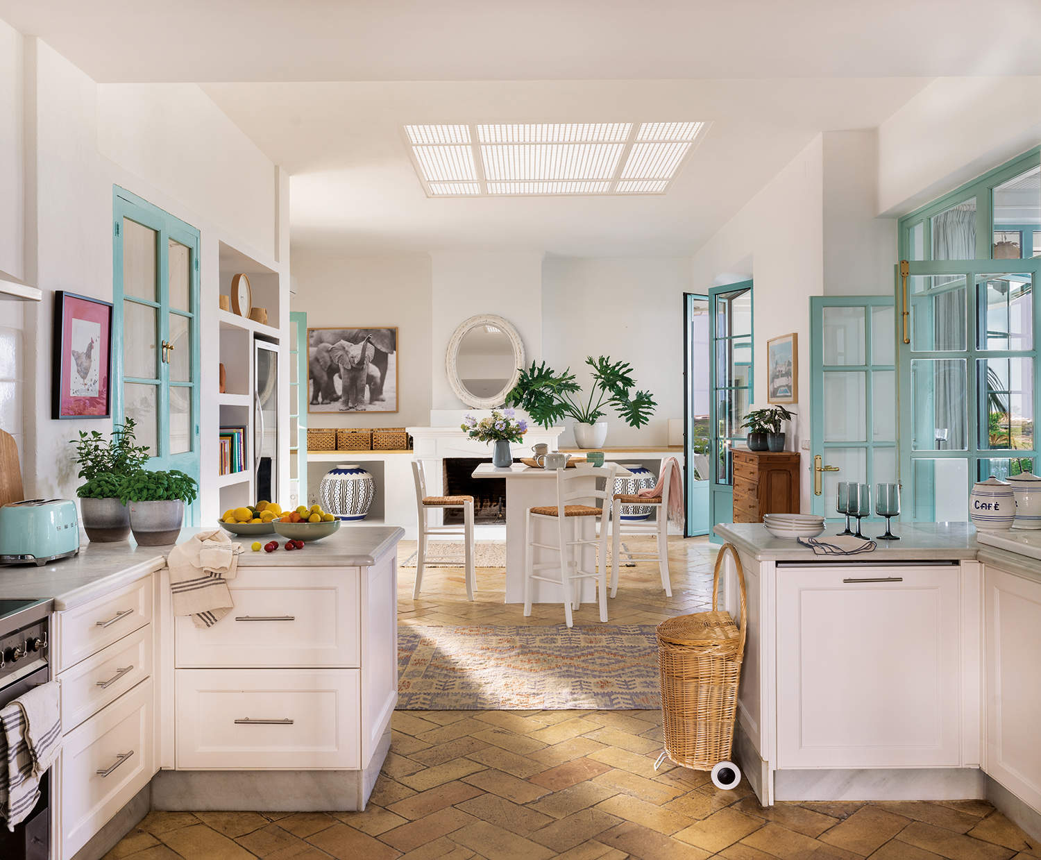Cocina rústica moderna blanca con suelo de barro y desayunador con sillas altas, carpintería azul