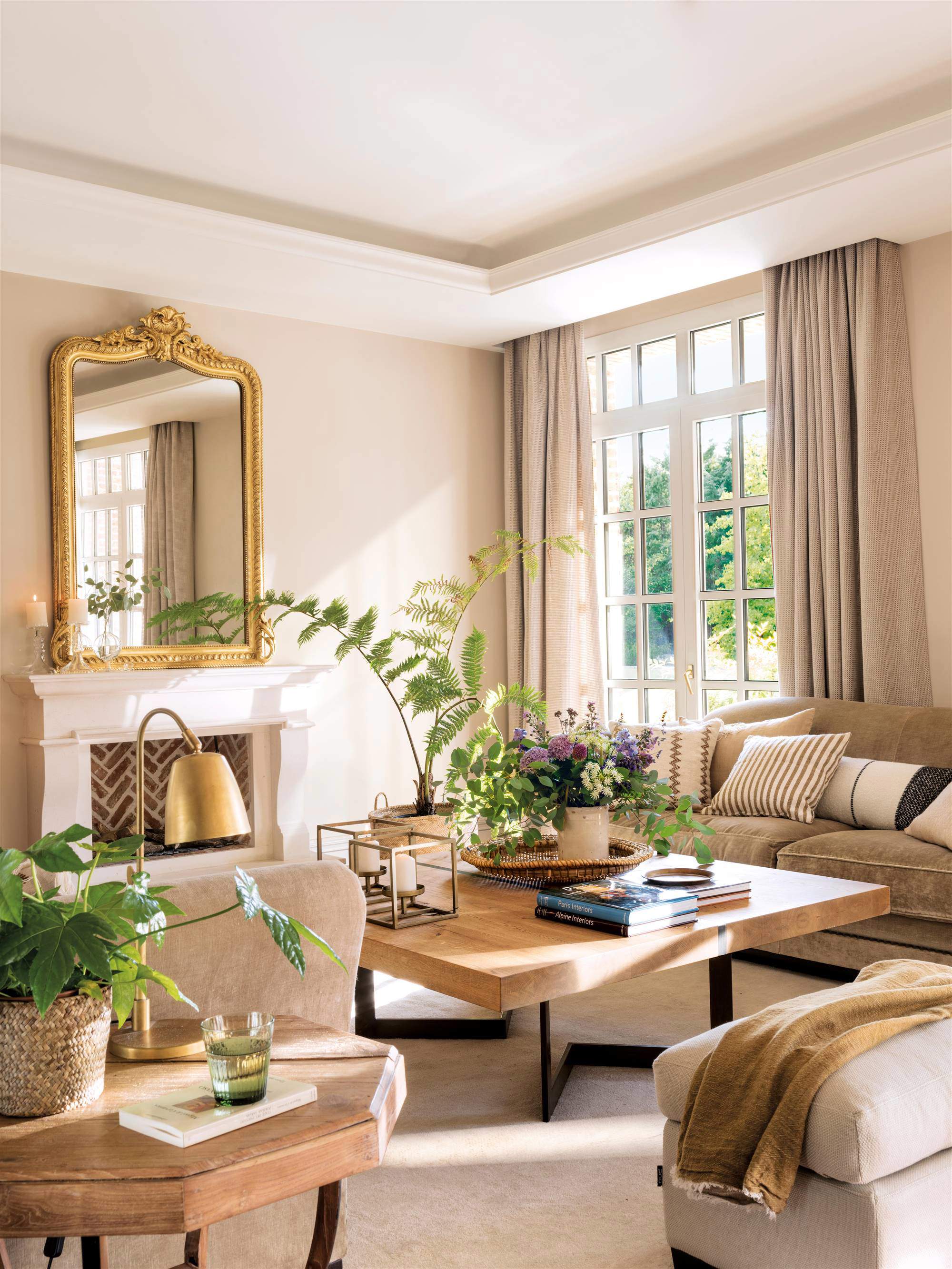 Salón con chimenea, sofás, mesa de centro, cortinas y espejo dorado