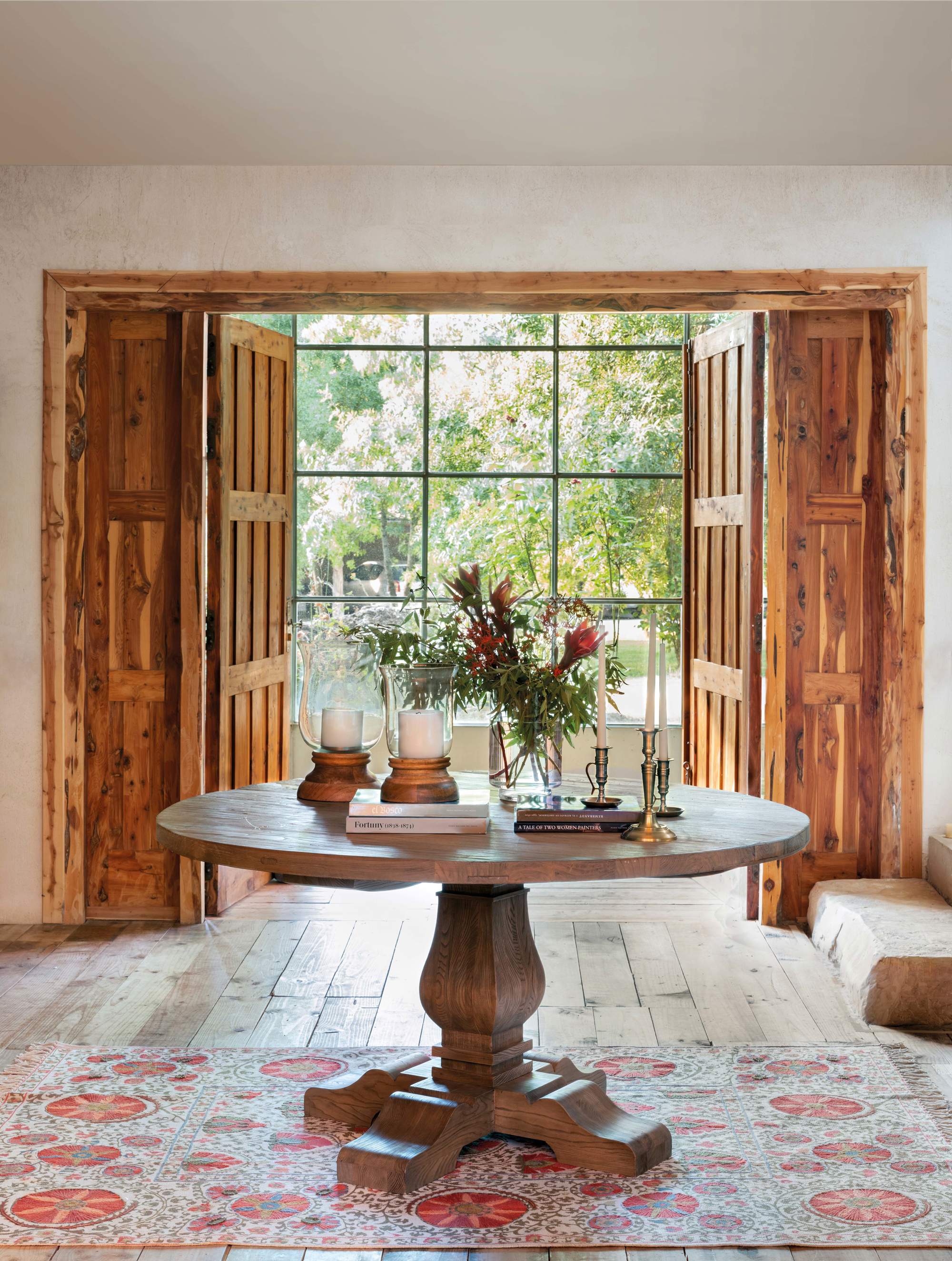Recibidor con mesa de madera maciza, alfombra y contraventanas de madera