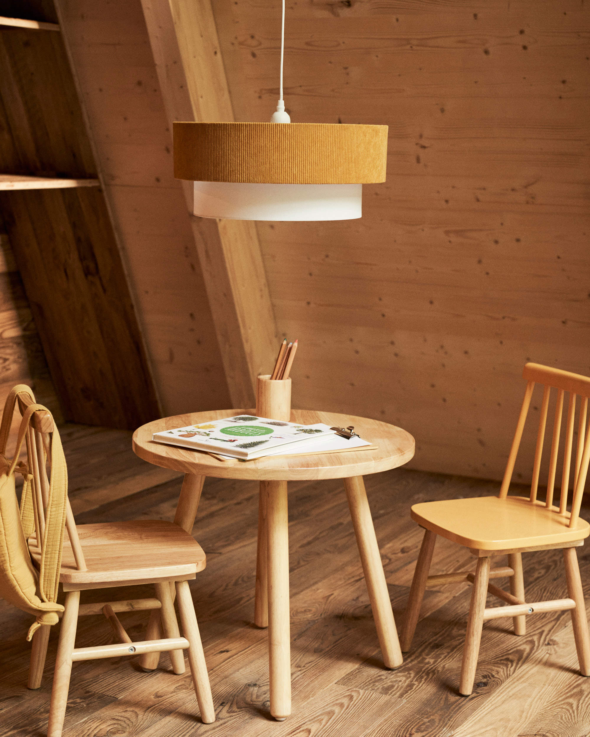 Zona de juegos infantil con mesa redonda y sillas de madera