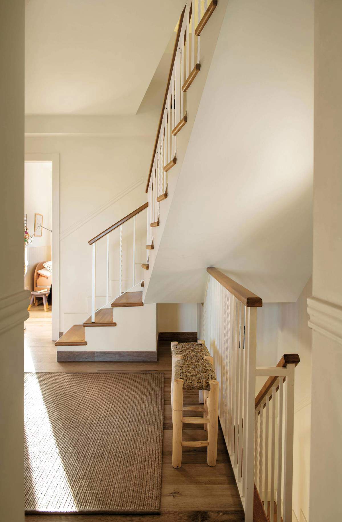 Descansillo de escalera decorado con un banco y una alfombra