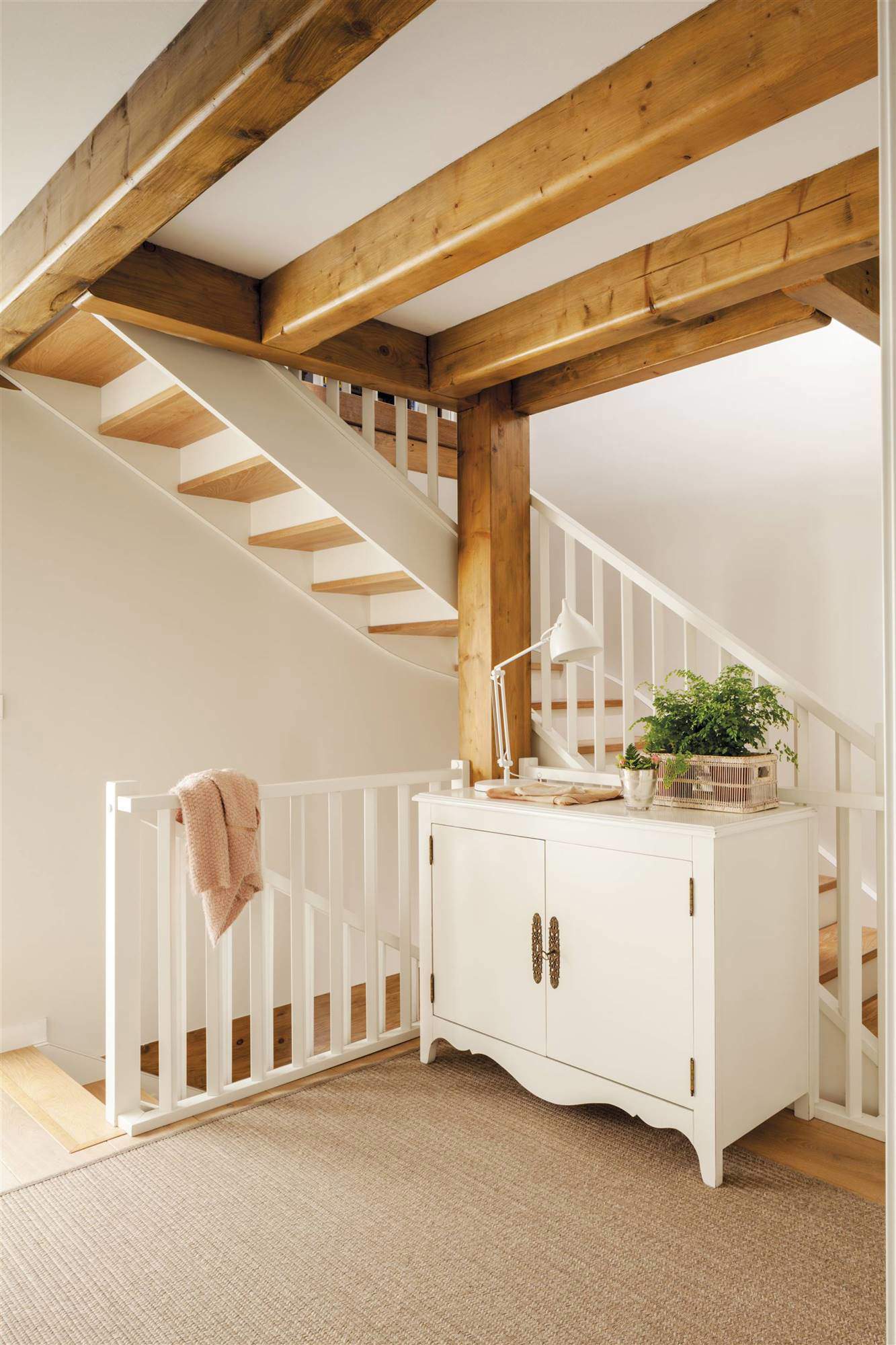 Descansillo de escaleras decorado con alfombra y aparador